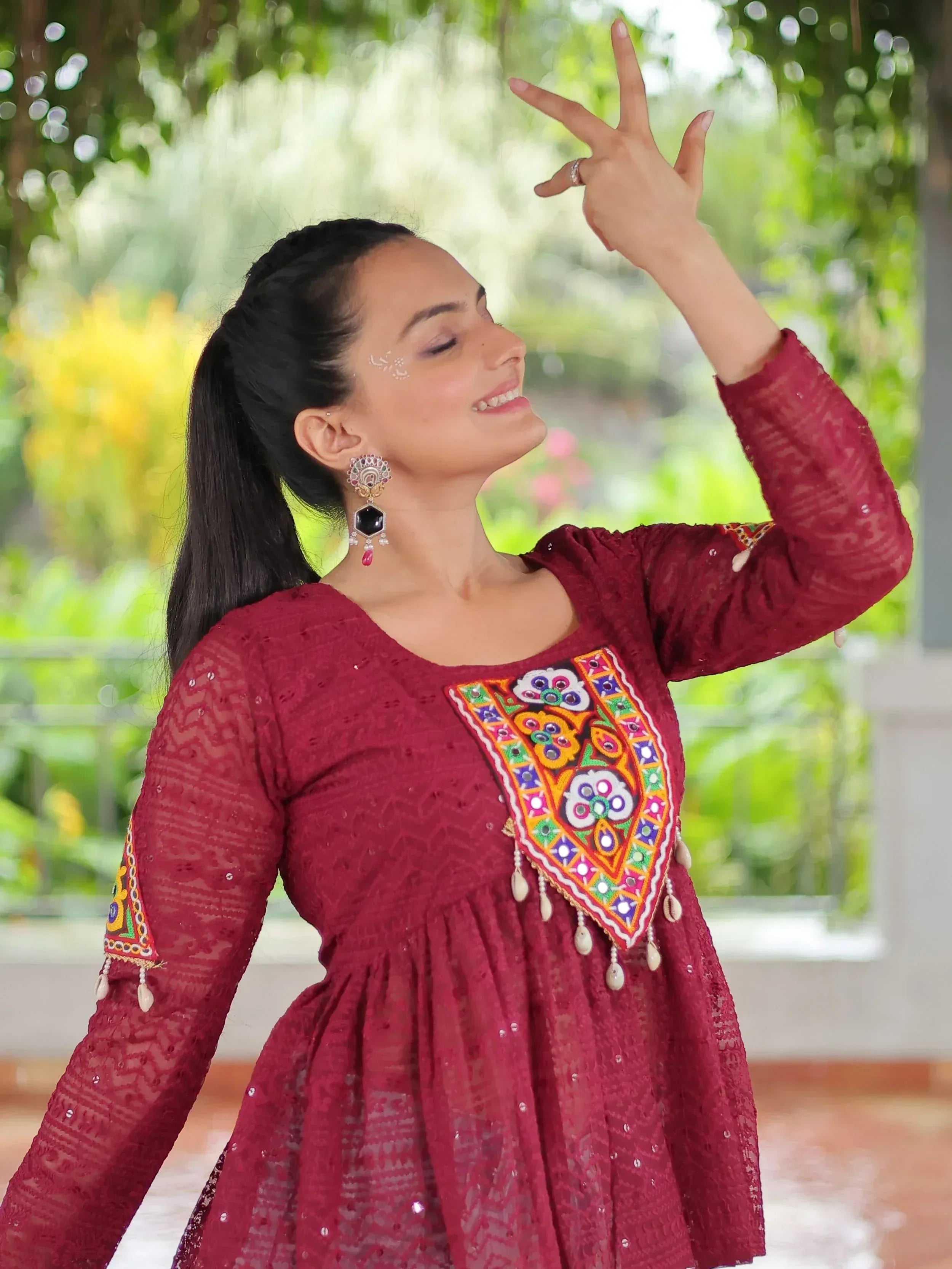Woman in maroon ethnic gown with mirror work, perfect for Indian festive wear and designer occasions.