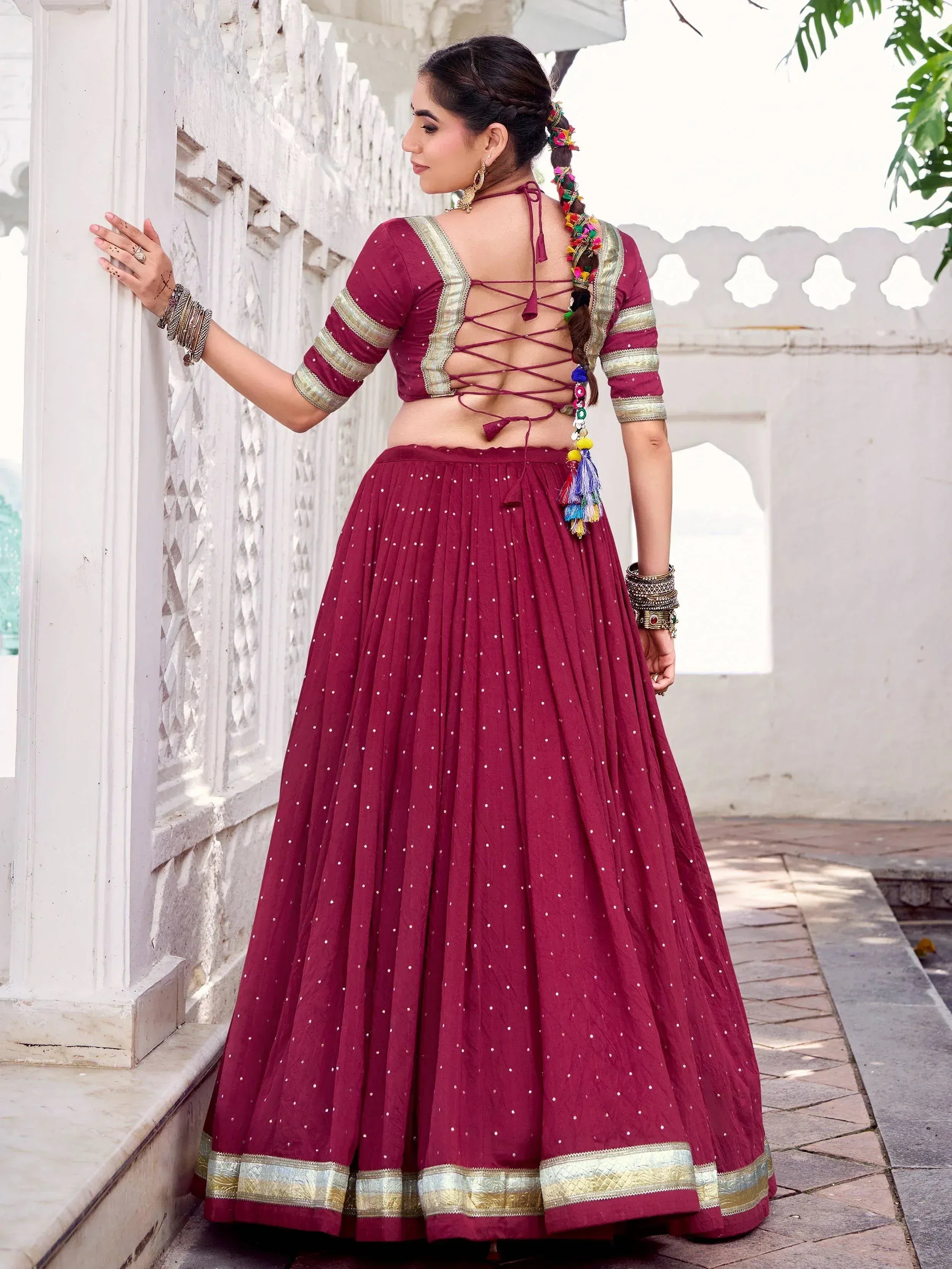 Maroon ethnic lehenga choli with back lace-up blouse, gold trim, and pleated skirt for Indian wear