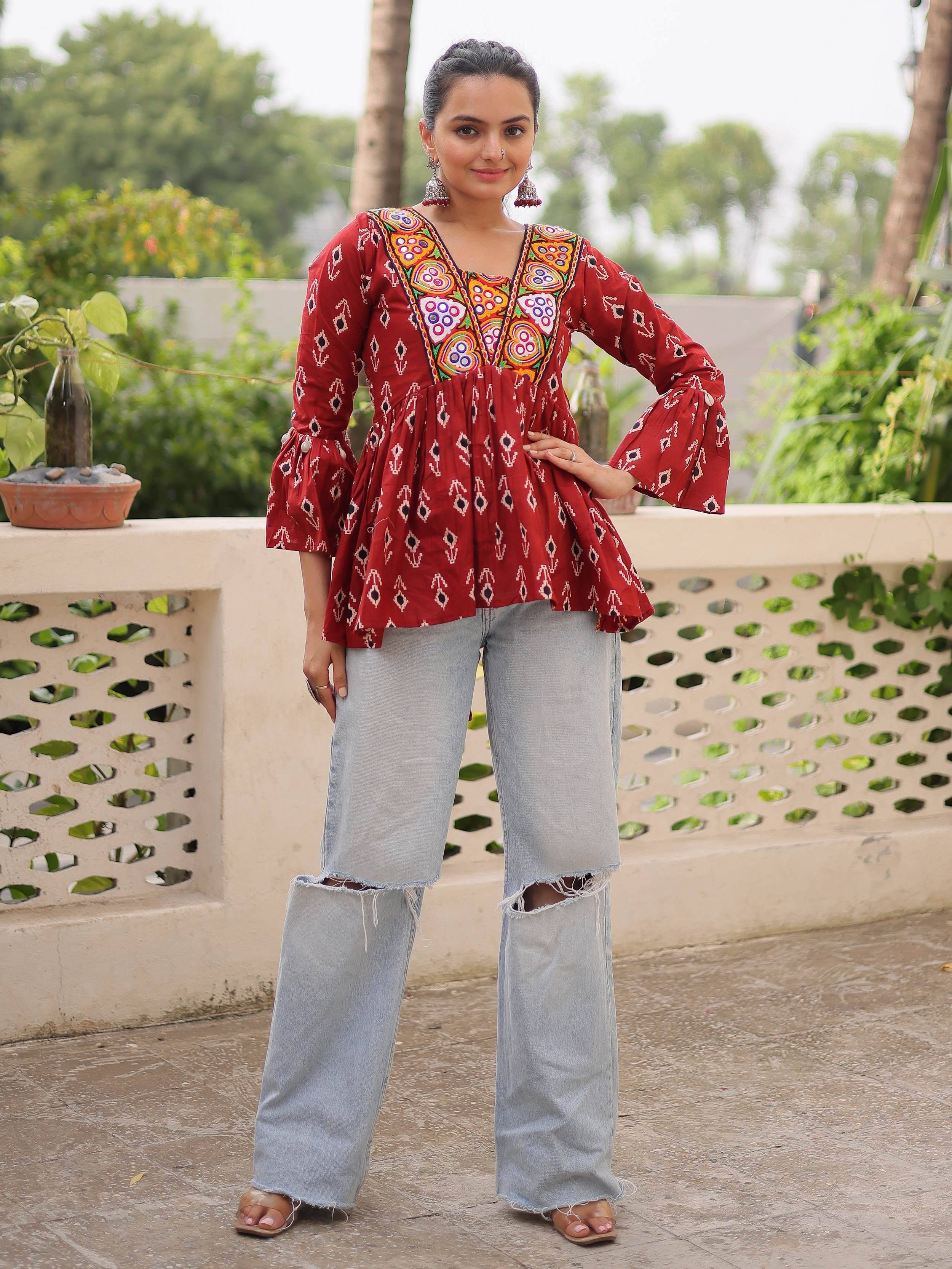 Red embroidered ethnic top with bell sleeves paired with ripped jeans, perfect for casual Indian wear.