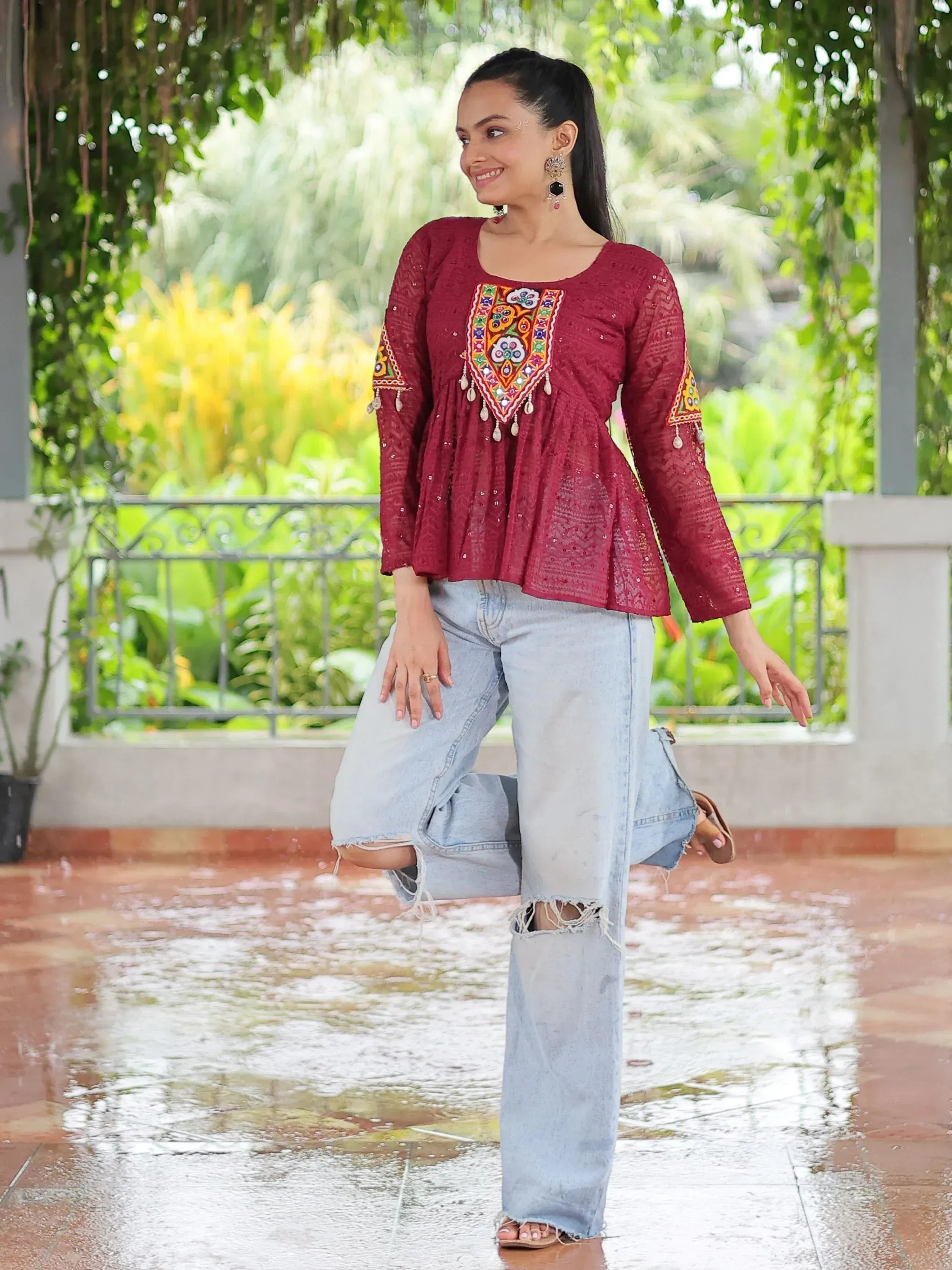 Maroon embroidered ethnic top with mirror work, paired with ripped jeans, perfect for casual Indian wear.