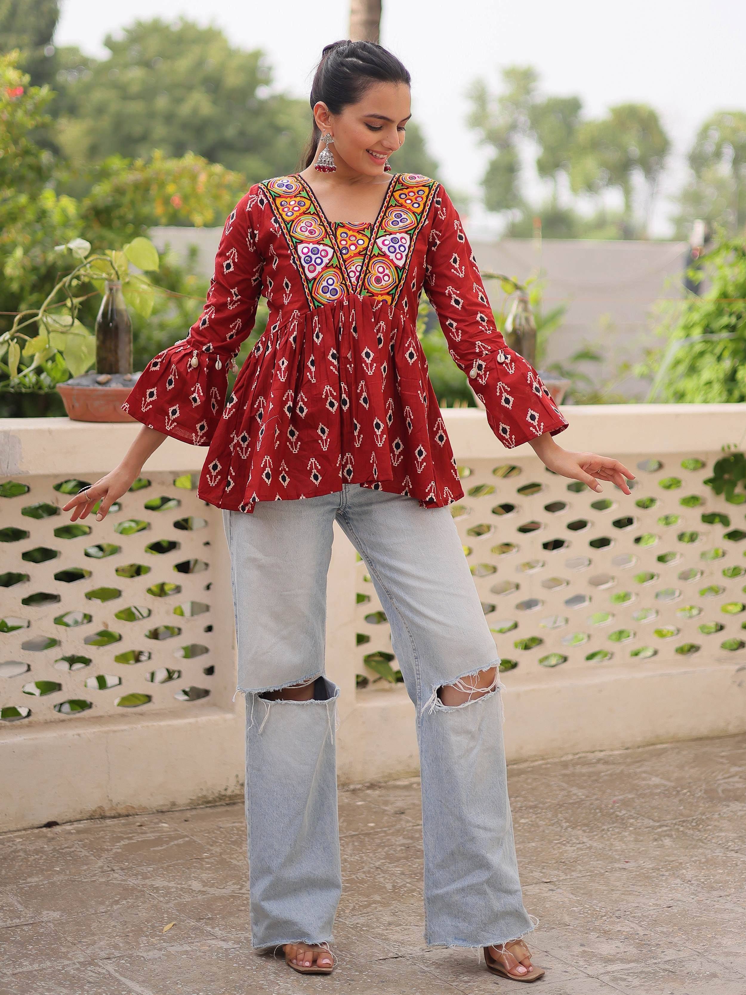 Red embroidered ethnic top with bell sleeves paired with ripped jeans, perfect for casual Indian wear
