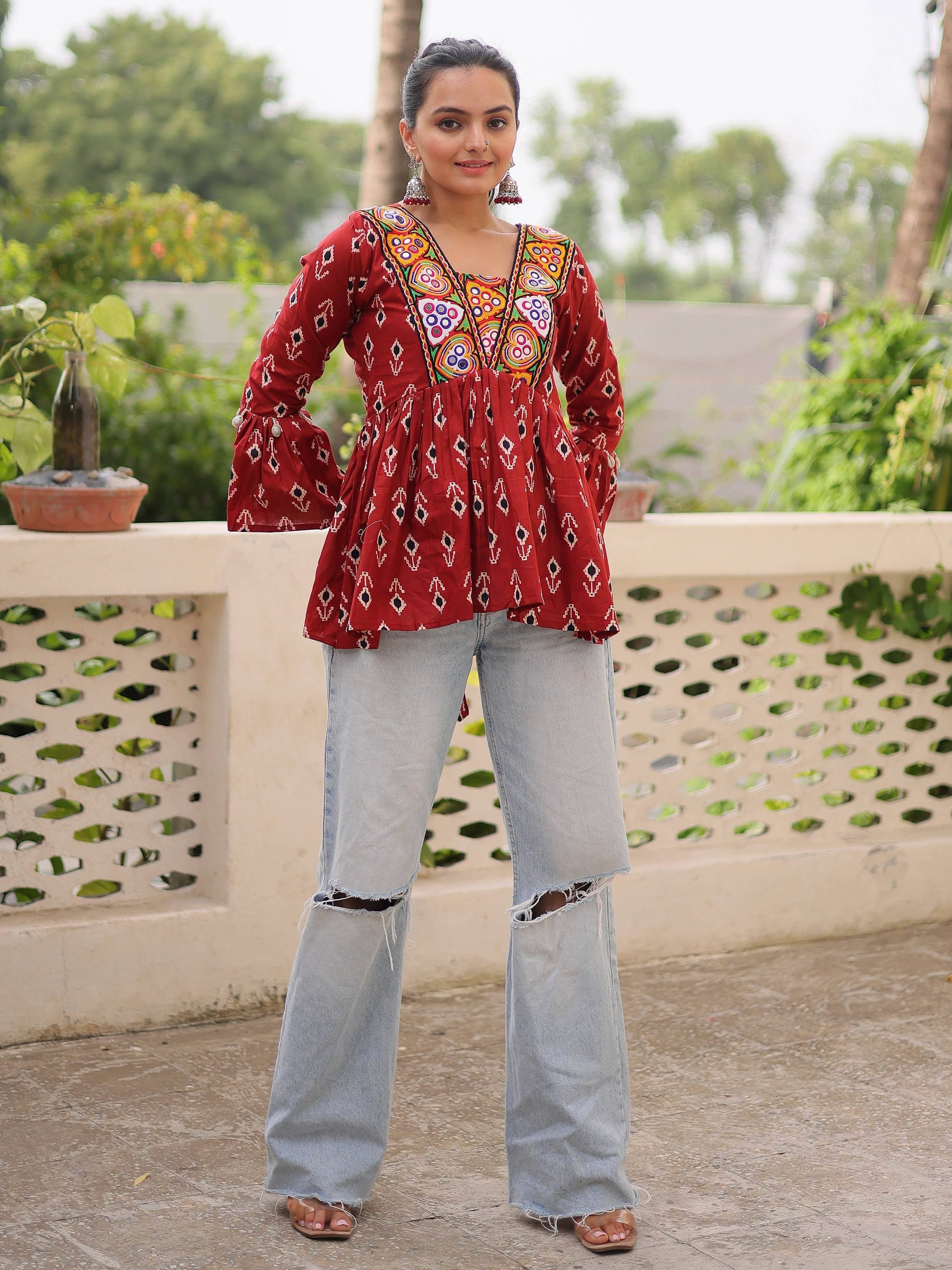 Red embroidered ethnic kurta with bell sleeves paired with ripped jeans, perfect for casual Indian wear.