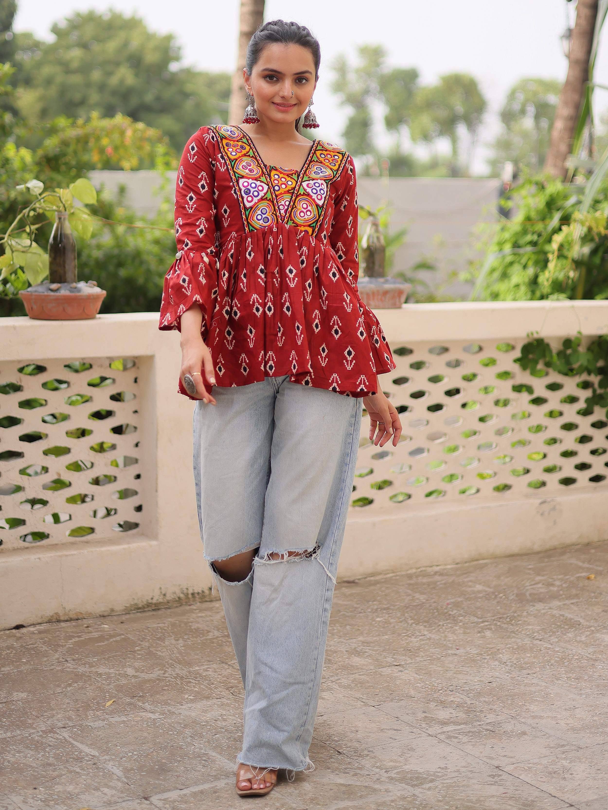 Red embroidered ethnic top with bell sleeves paired with ripped wide-leg jeans, perfect for casual Indian wear.