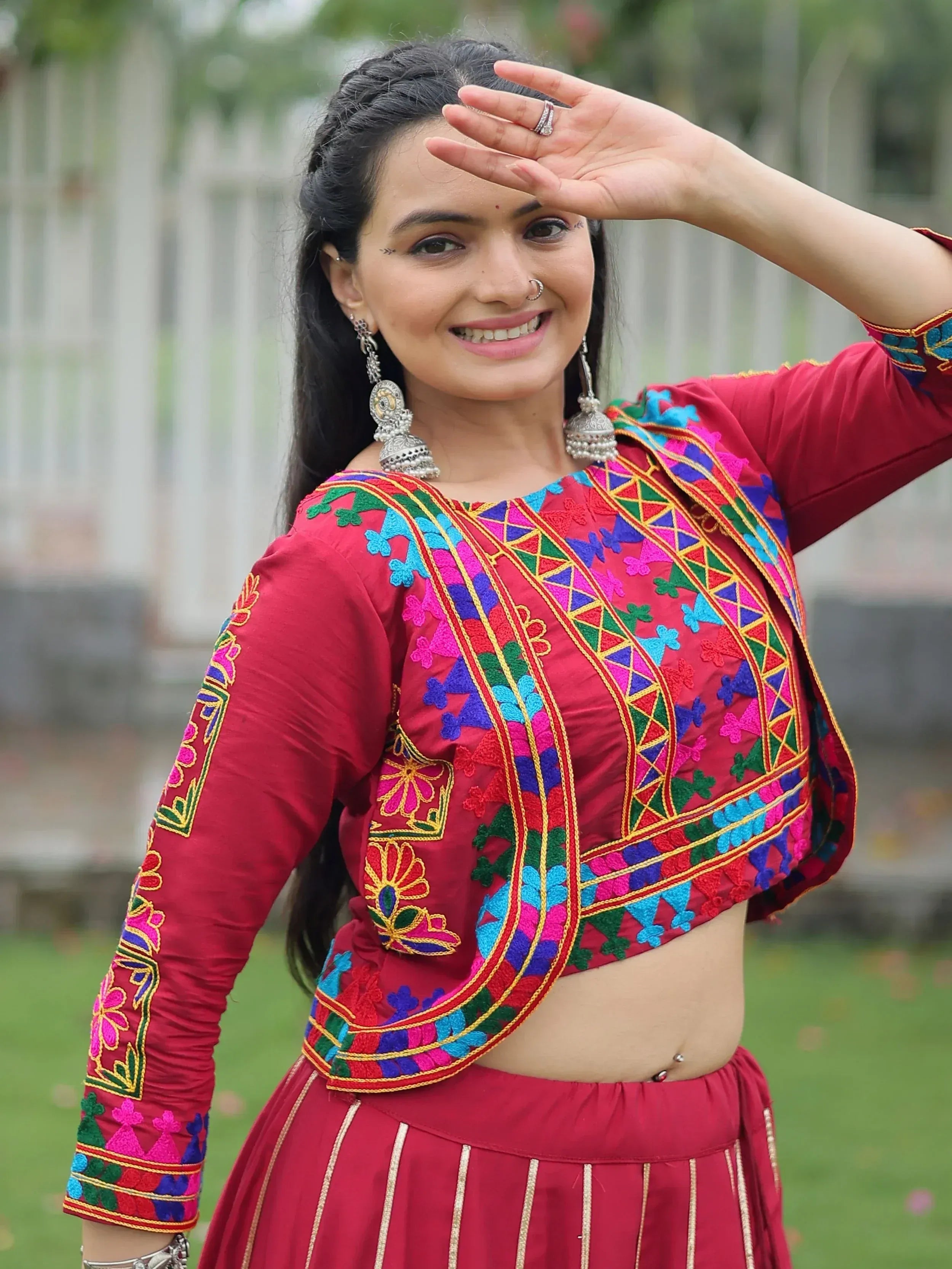 Vibrant red embroidered ethnic top with colorful patterns, paired with matching skirt, perfect for festive occasions.