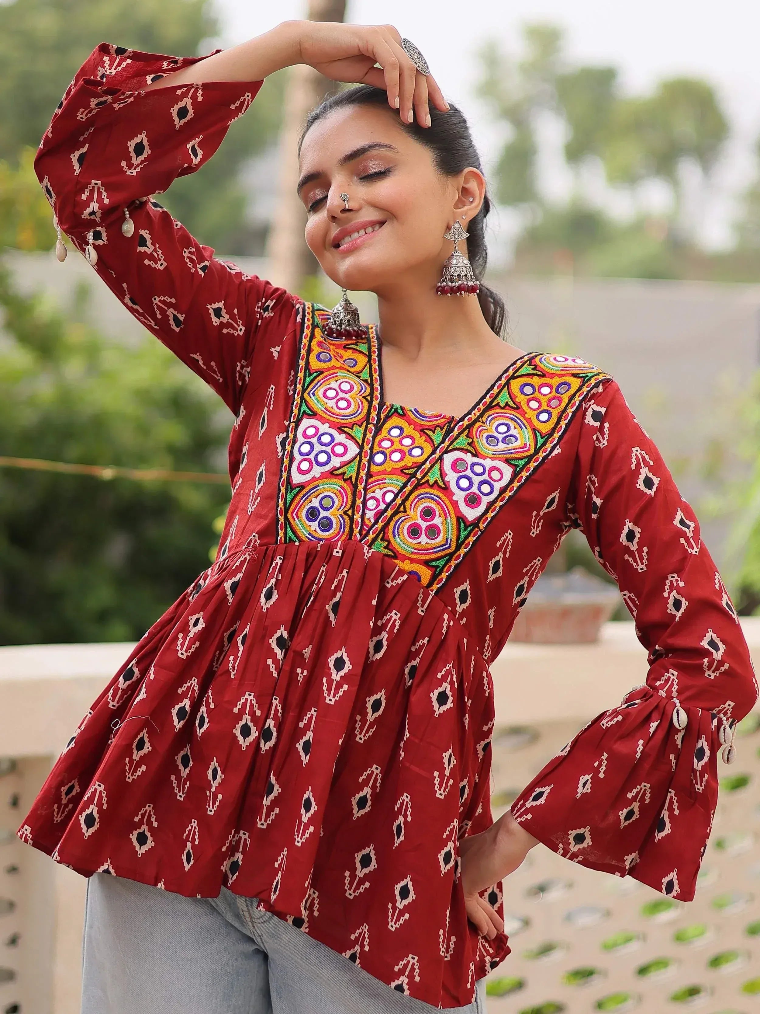 Red ethnic kurti with mirror work and bell sleeves, paired with jeans for casual wear