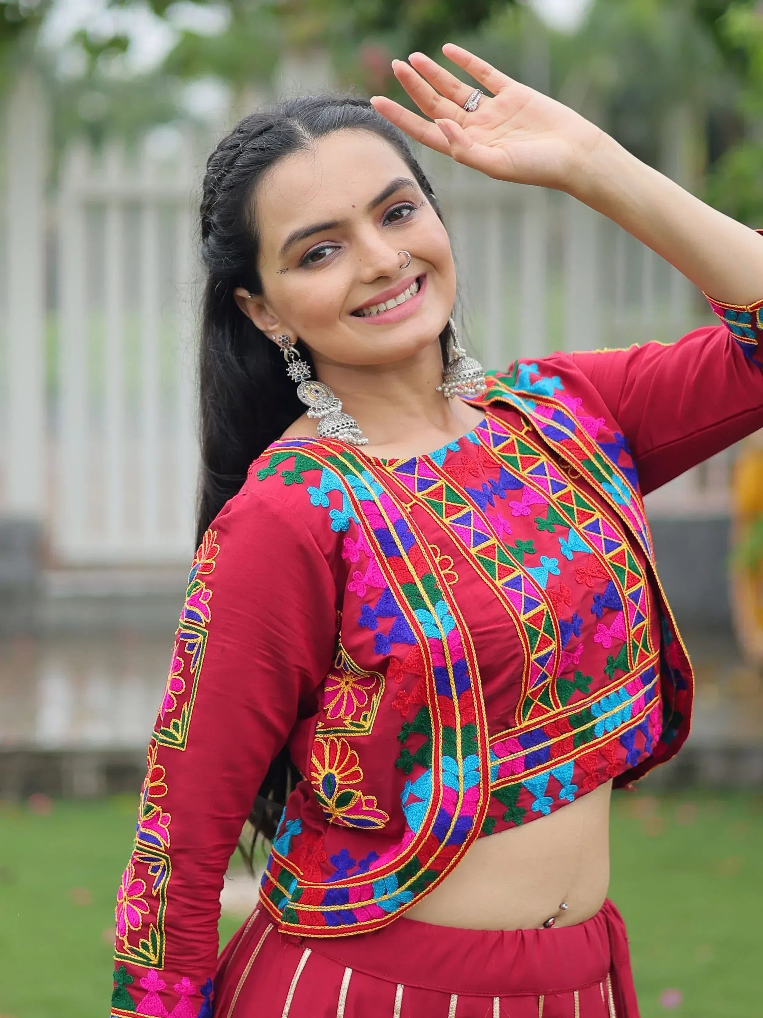 Vibrant red embroidered crop top with colorful floral patterns, paired with matching skirt for festive Indian ethnic wear.