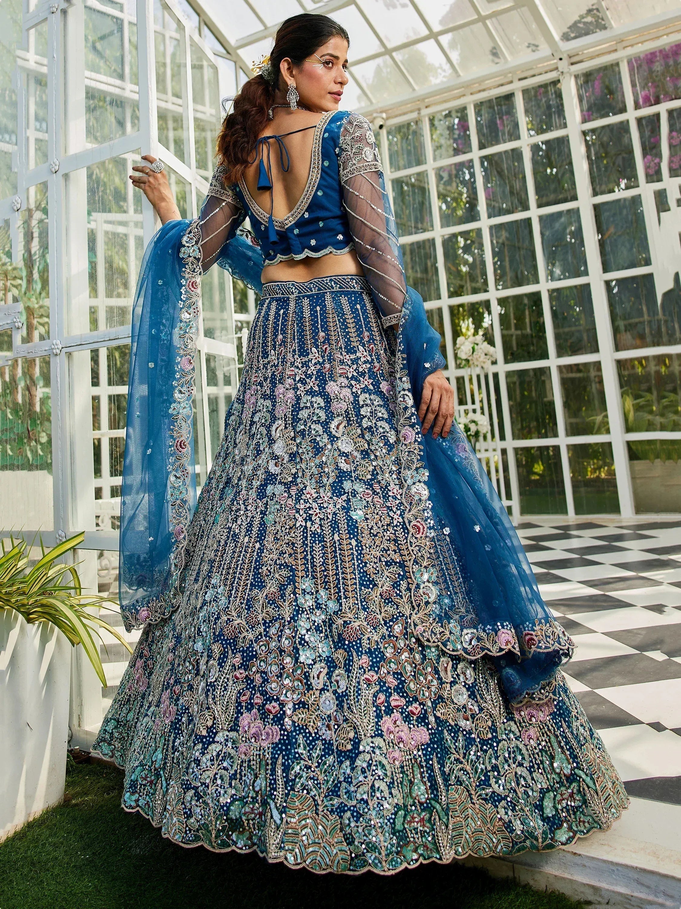 Blue embroidered lehenga choli with sheer sleeves, floral motifs, and back tie detail, perfect for Indian weddings.