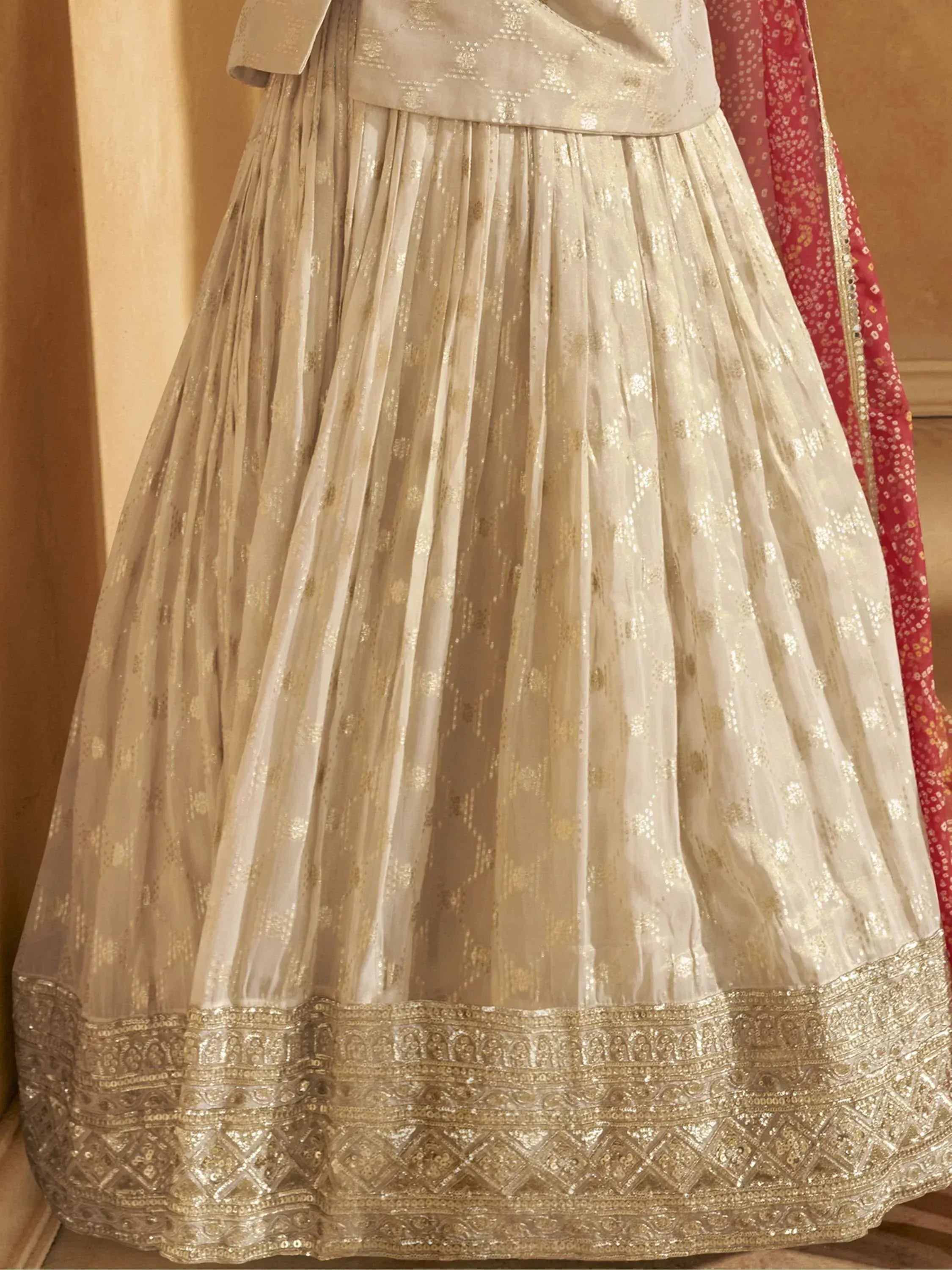 Cream and gold embroidered lehenga with intricate border and red dupatta, perfect for Indian ethnic wear