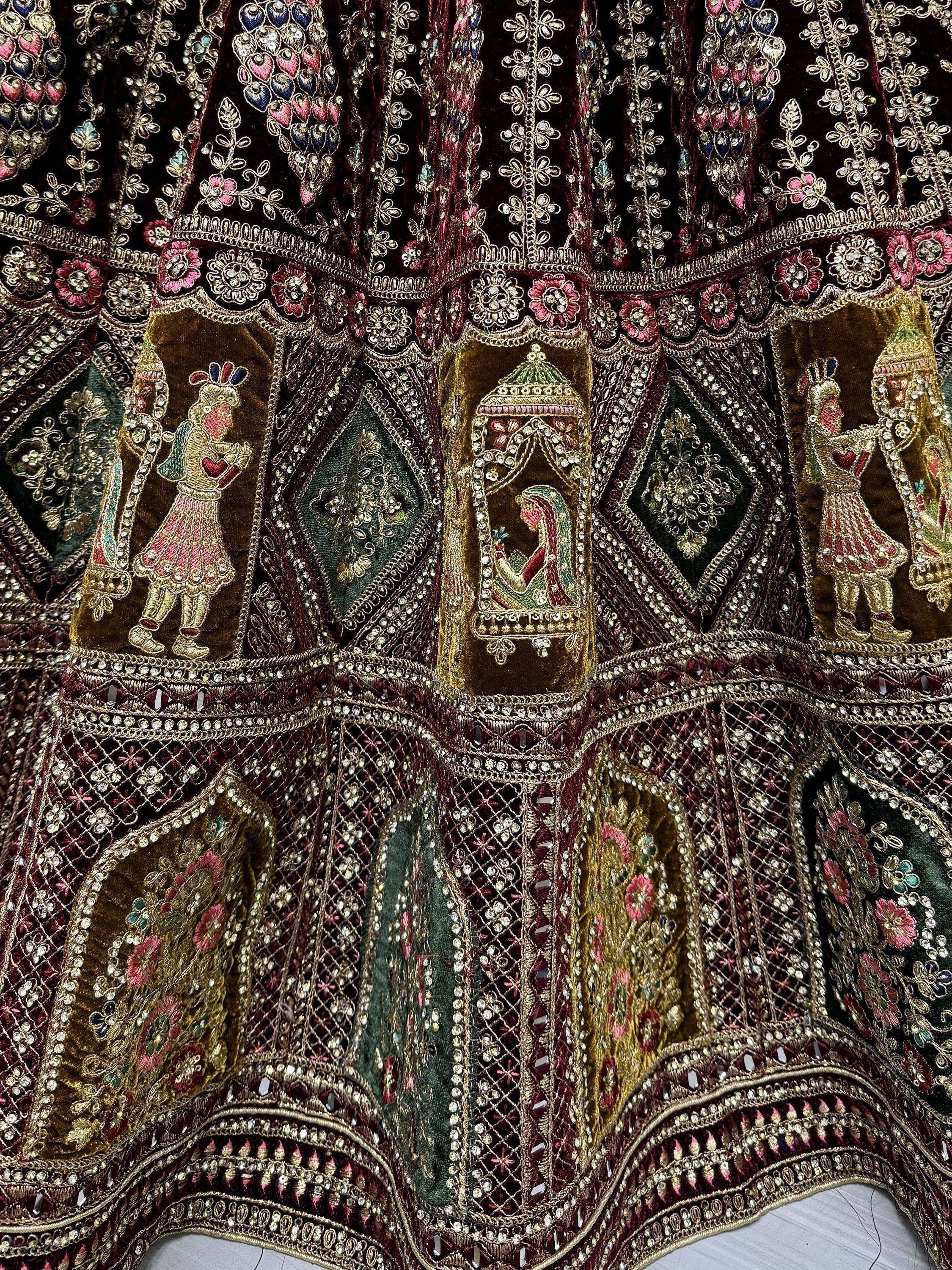 Luxury Indian ethnic lehenga with intricate embroidery, mirror work, and royal motifs in maroon and gold.