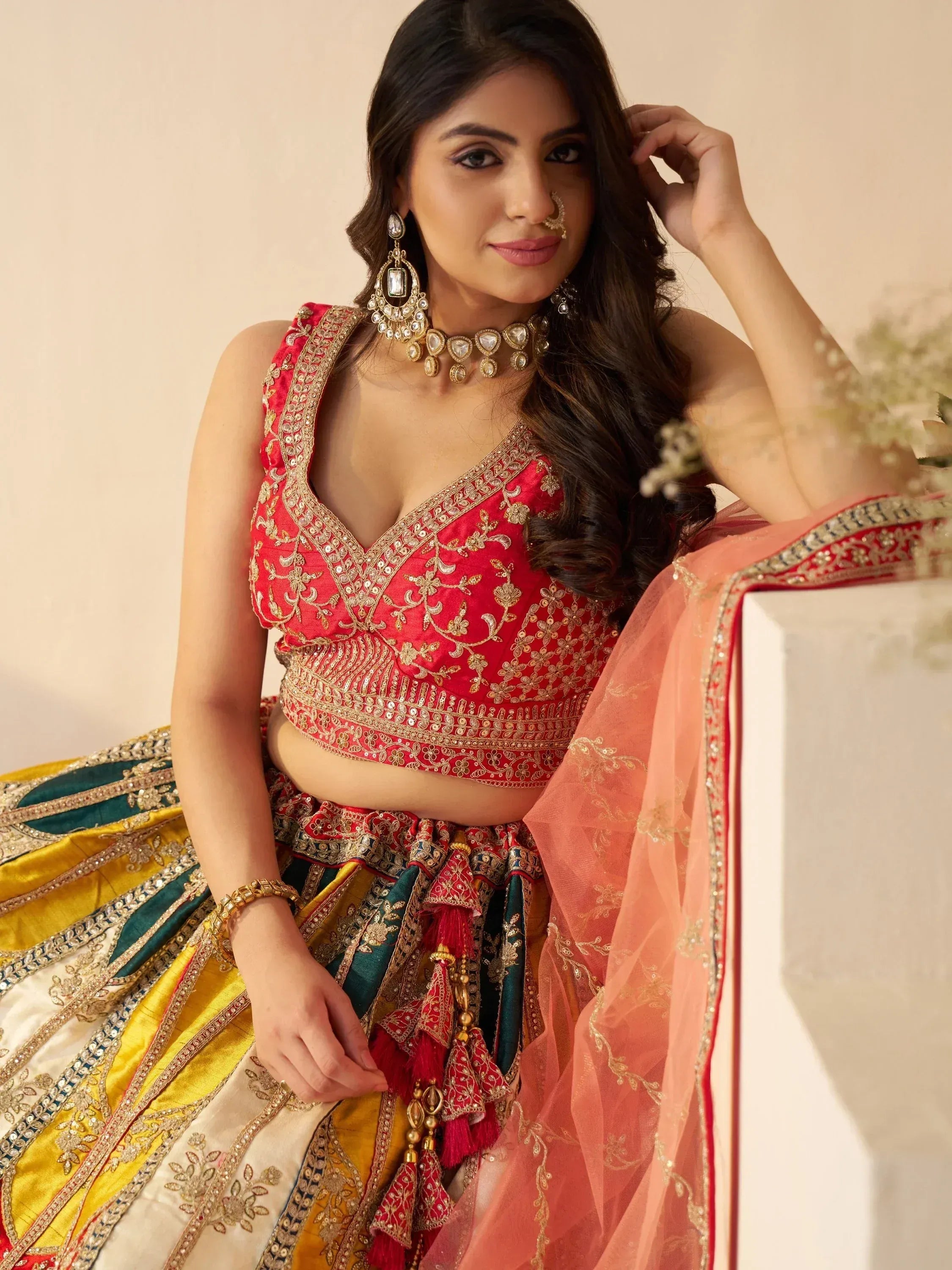 Red embroidered lehenga choli with gold detailing, peach dupatta, and traditional Indian jewelry