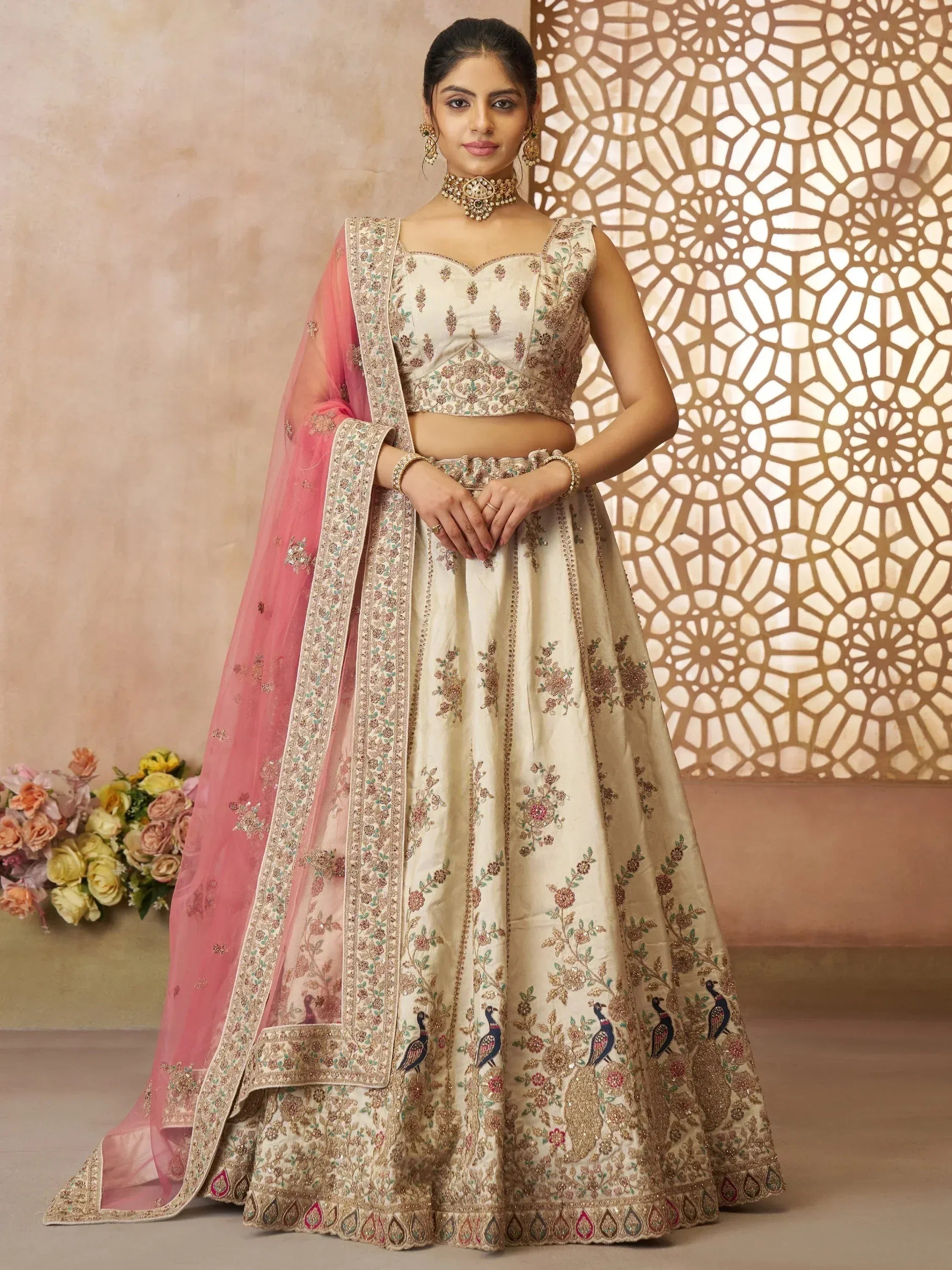 Cream embroidered lehenga choli with pink dupatta, floral and peacock motifs, perfect for Indian weddings and festivals.