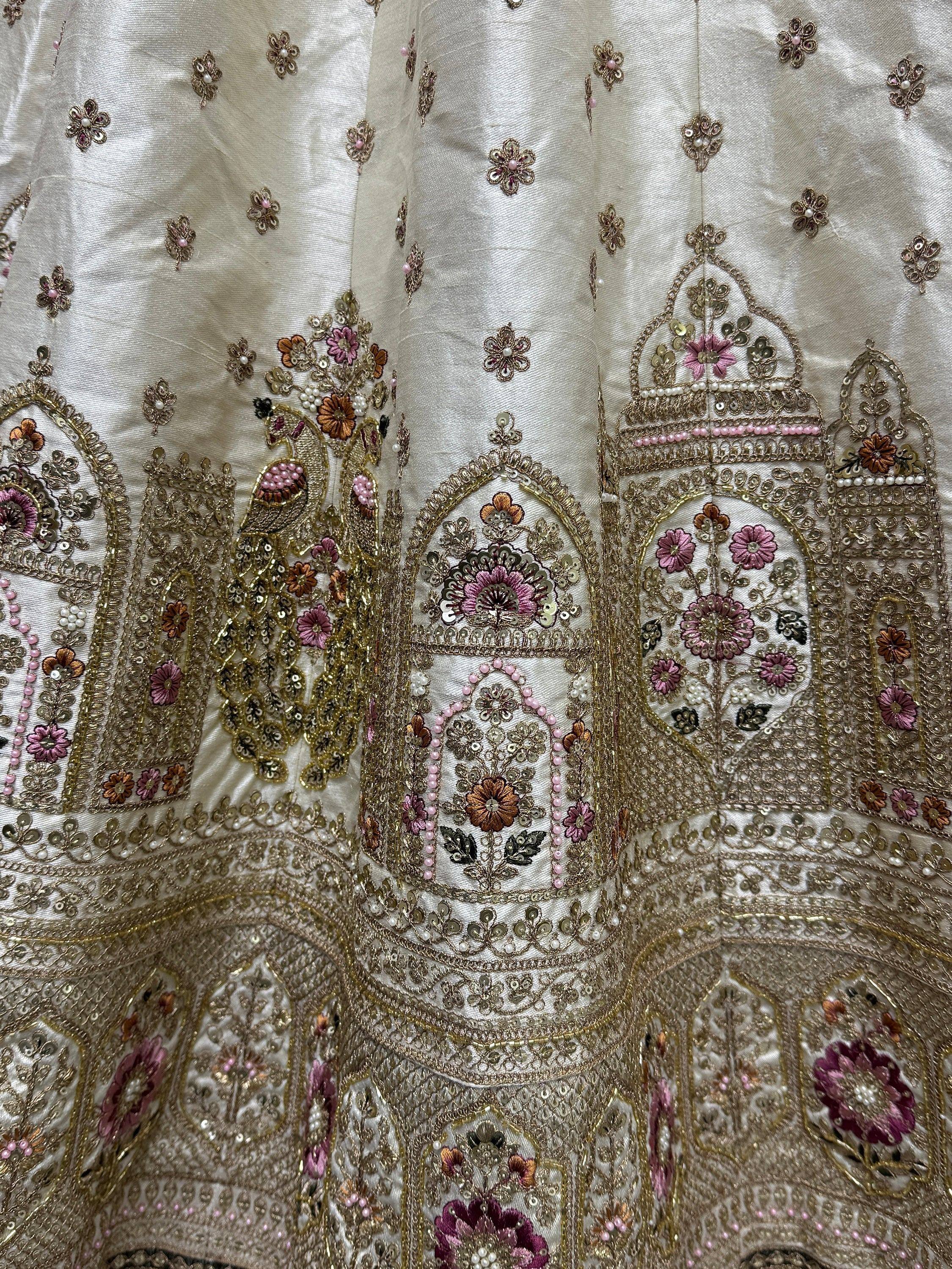 Elegant ivory lehenga with gold embroidery, pink floral motifs, and pearl detailing for Indian ethnic wear.
