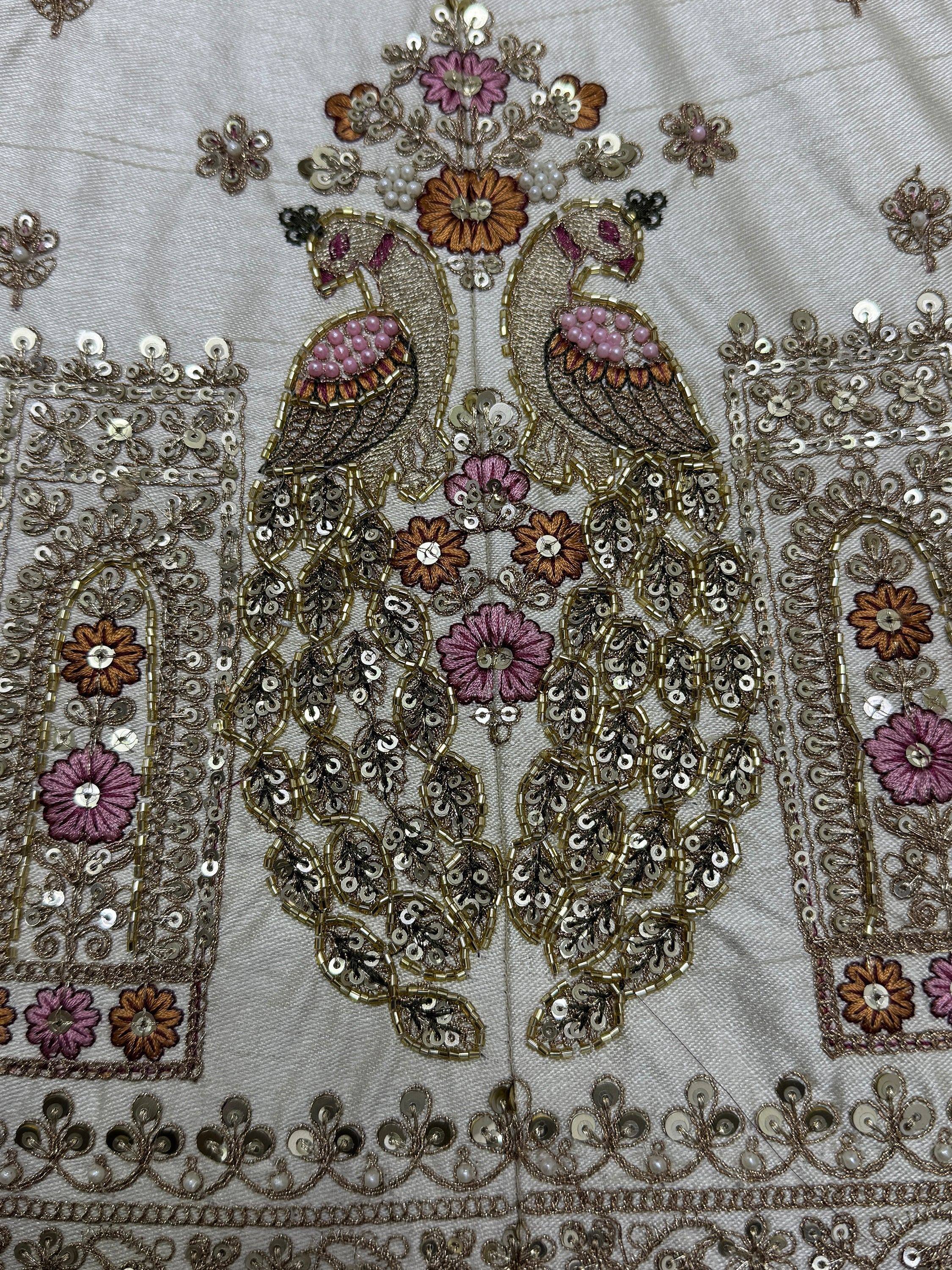 Intricate Indian ethnic wear embroidery with peacock, floral motifs, beads, and sequins on light fabric