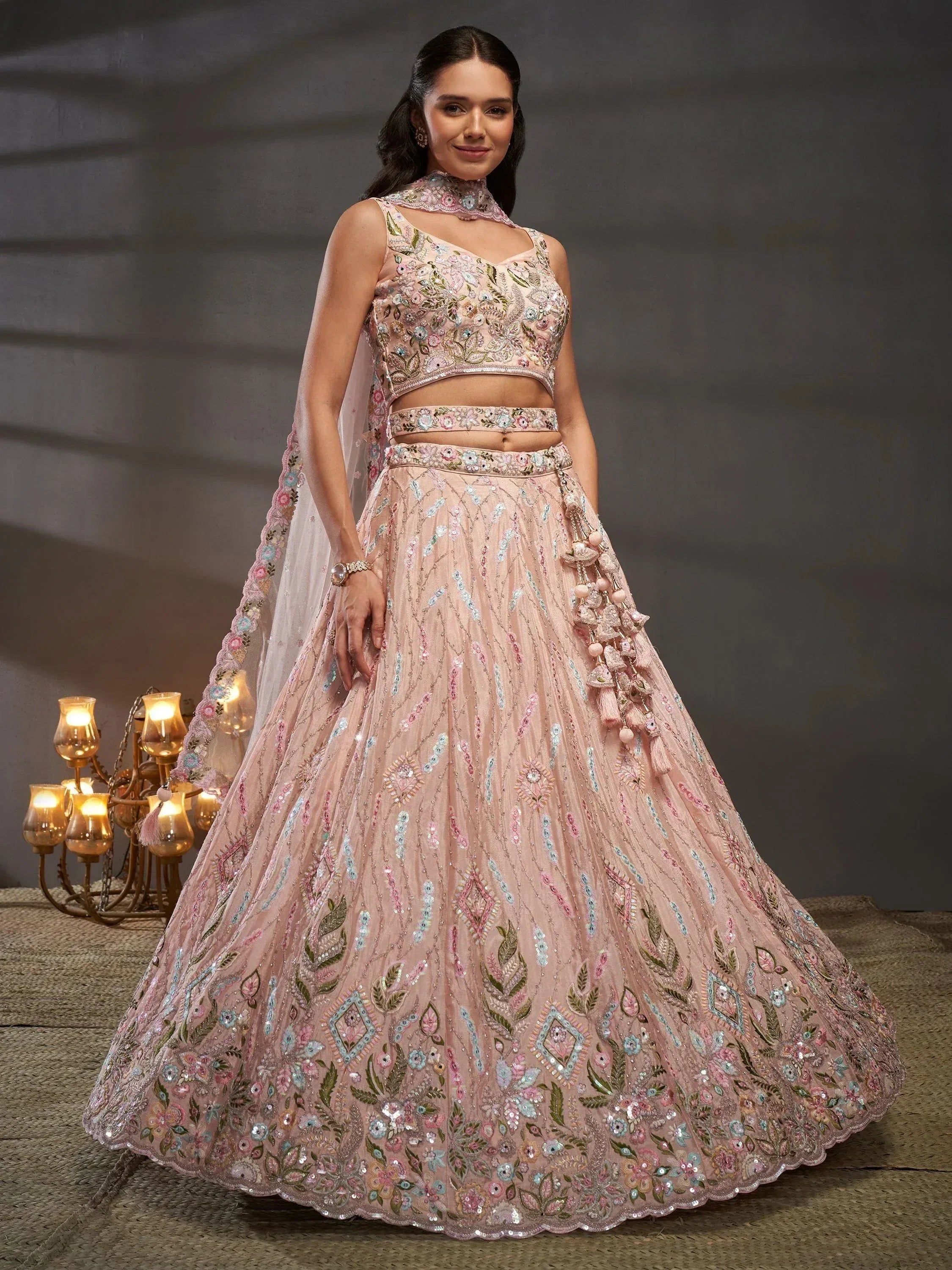 Pink embroidered lehenga choli with floral motifs and tassels, perfect for Indian weddings and festive occasions