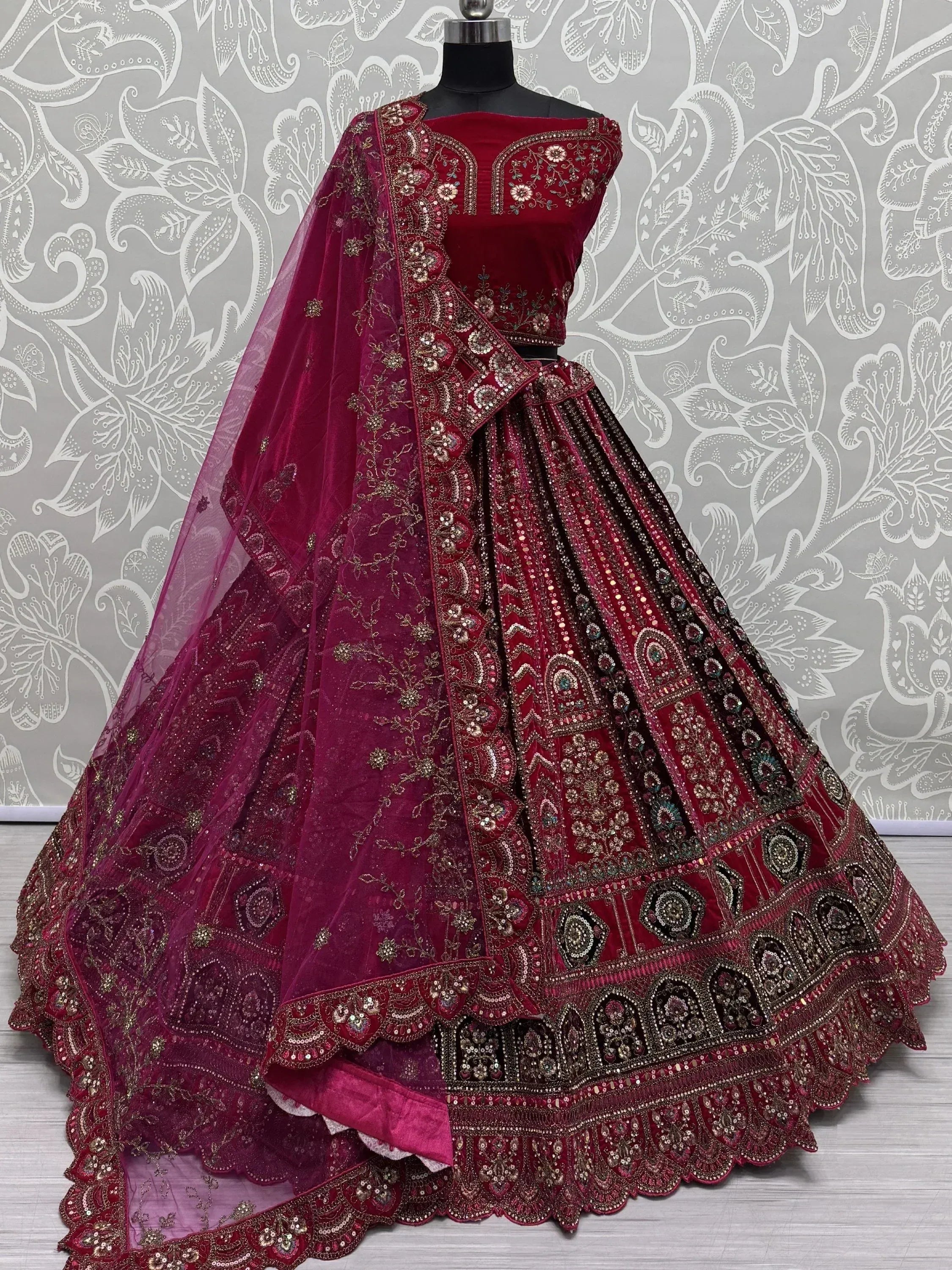 Burgundy velvet lehenga choli with heavy gold embroidery and matching dupatta, ideal for Indian weddings and festive occasions.