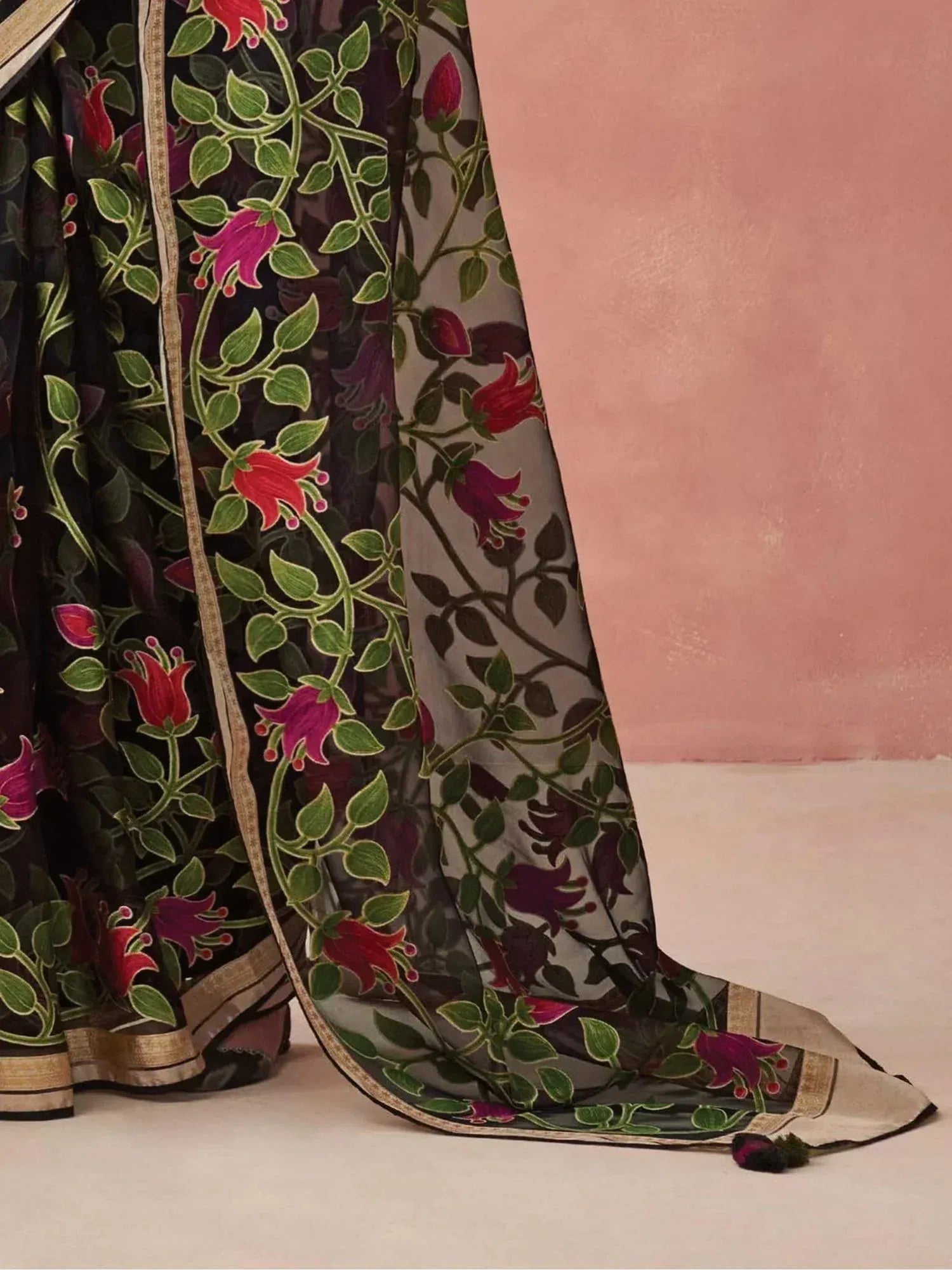 Black floral saree with red and pink blossoms, green leaves, and gold border, ideal for Indian ethnic wear