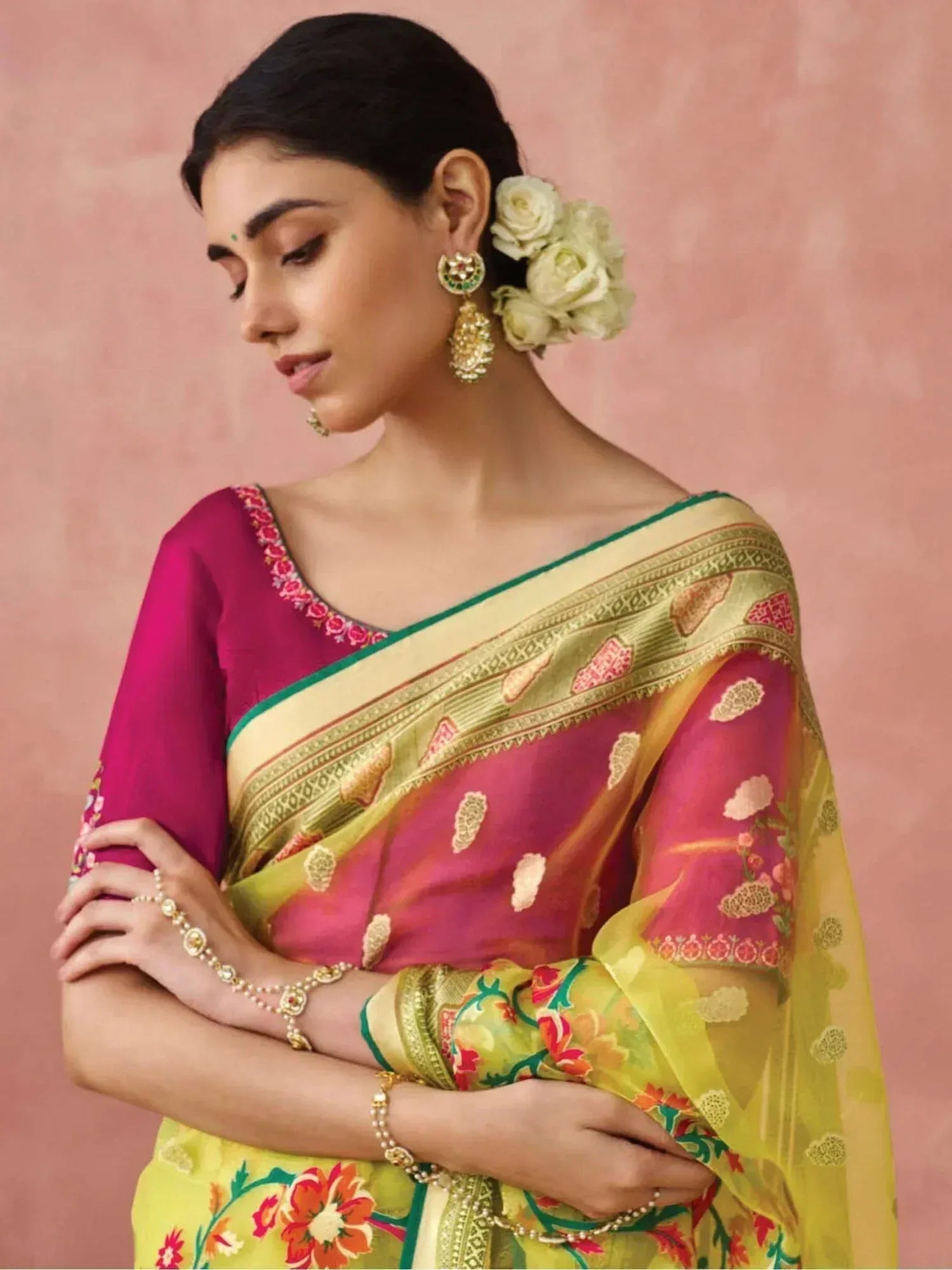 Woman in vibrant pink and yellow floral saree with gold embroidery, traditional Indian ethnic wear