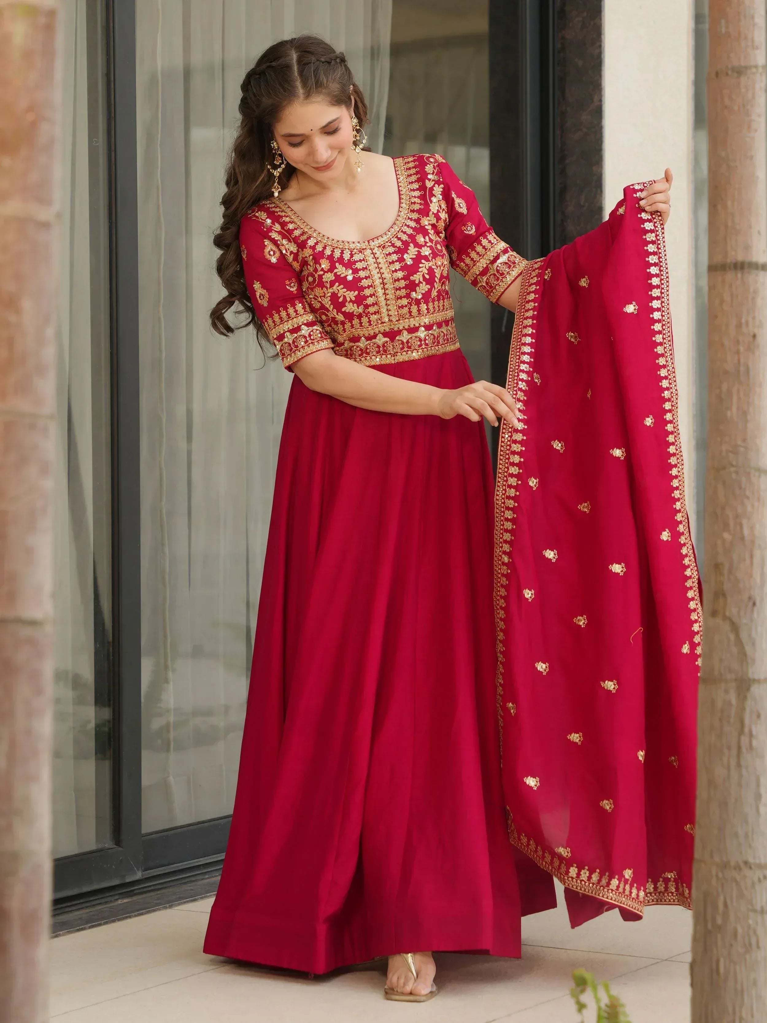 Woman in maroon ethnic anarkali with gold embroidery and matching dupatta, ideal for Indian weddings or festive occasions.