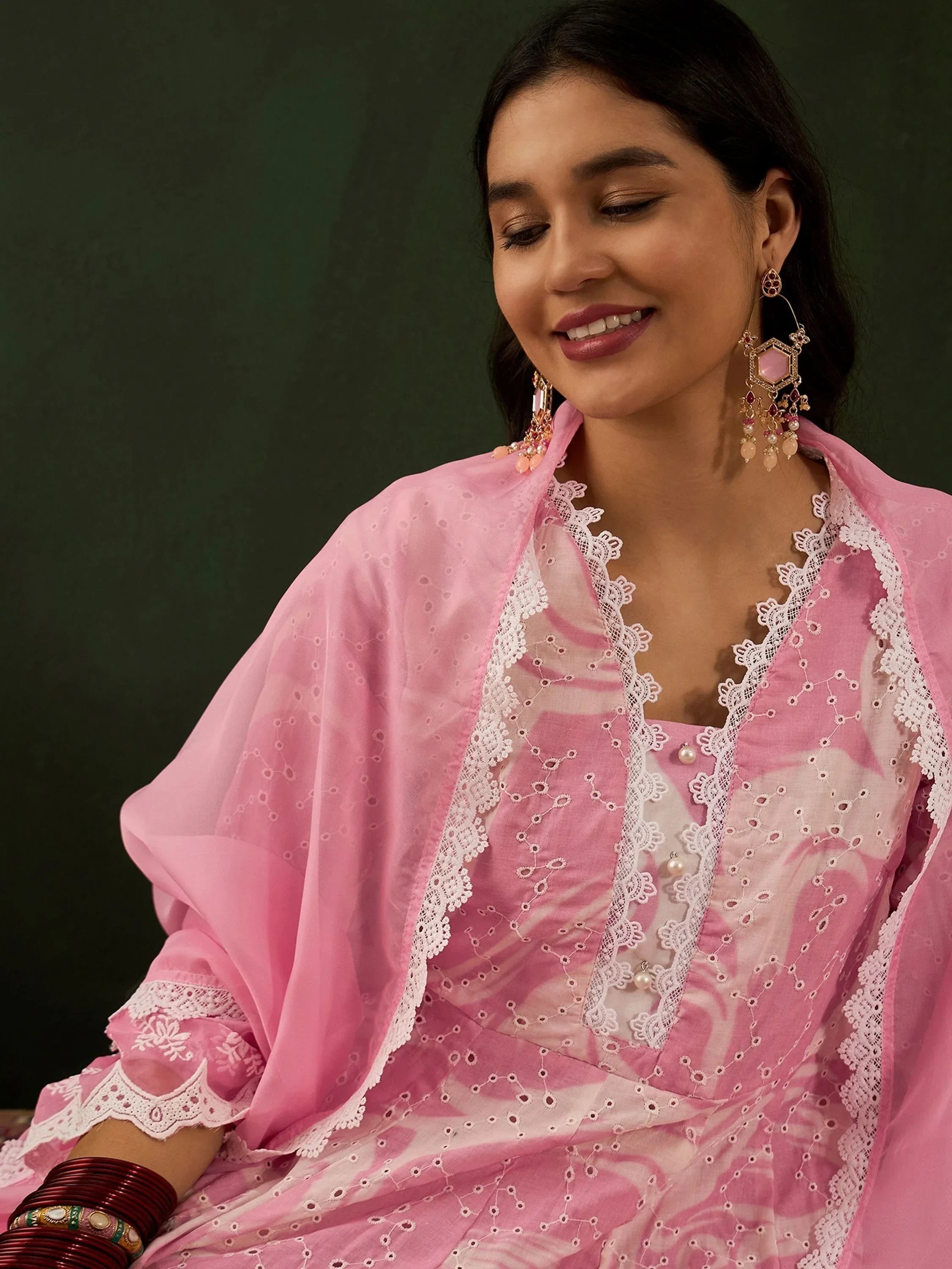 Woman in pink embroidered ethnic salwar kameez with lace details and statement earrings