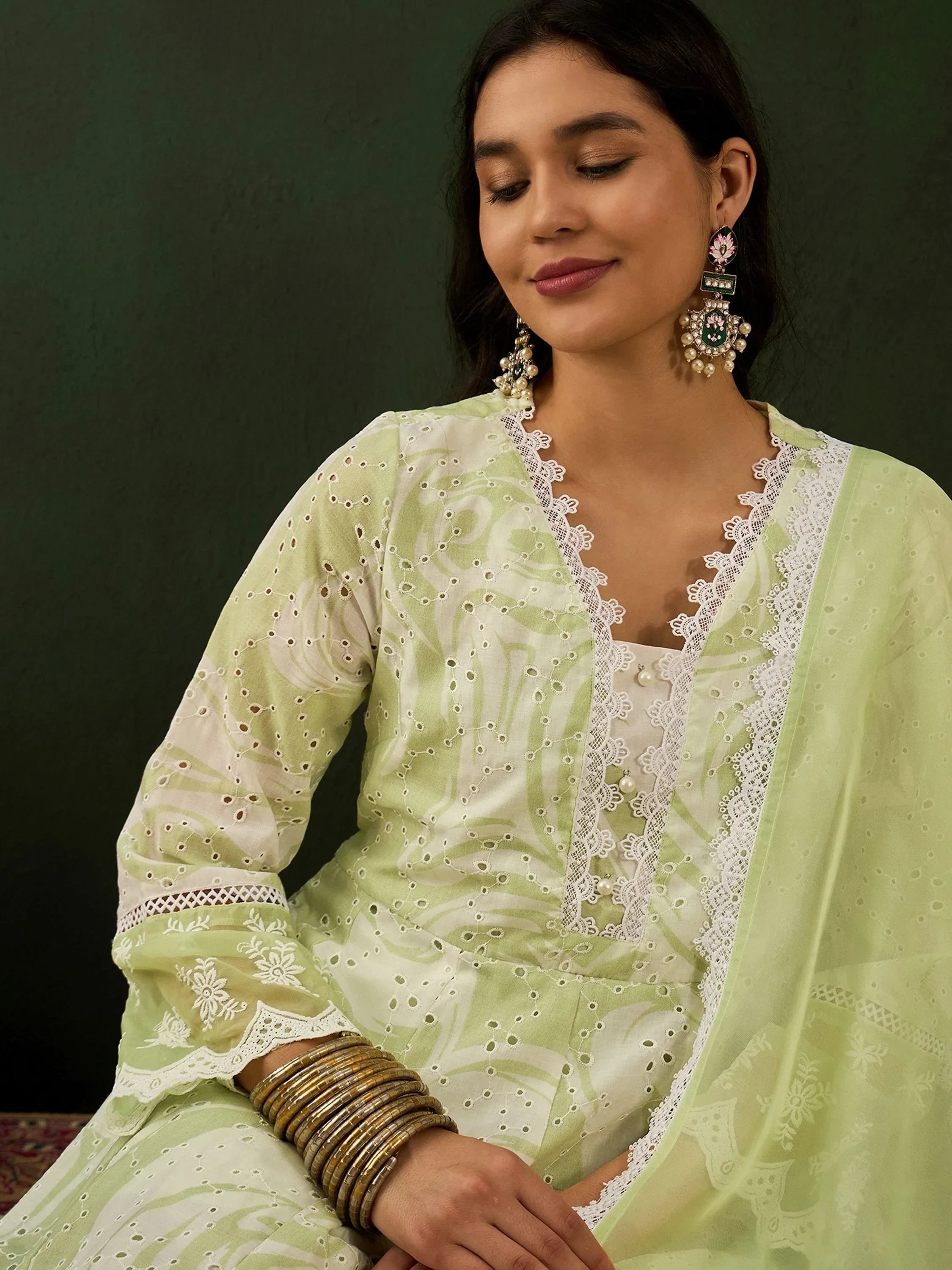 Woman in pastel green embroidered ethnic salwar kameez with dupatta, jewelry, and bangles
