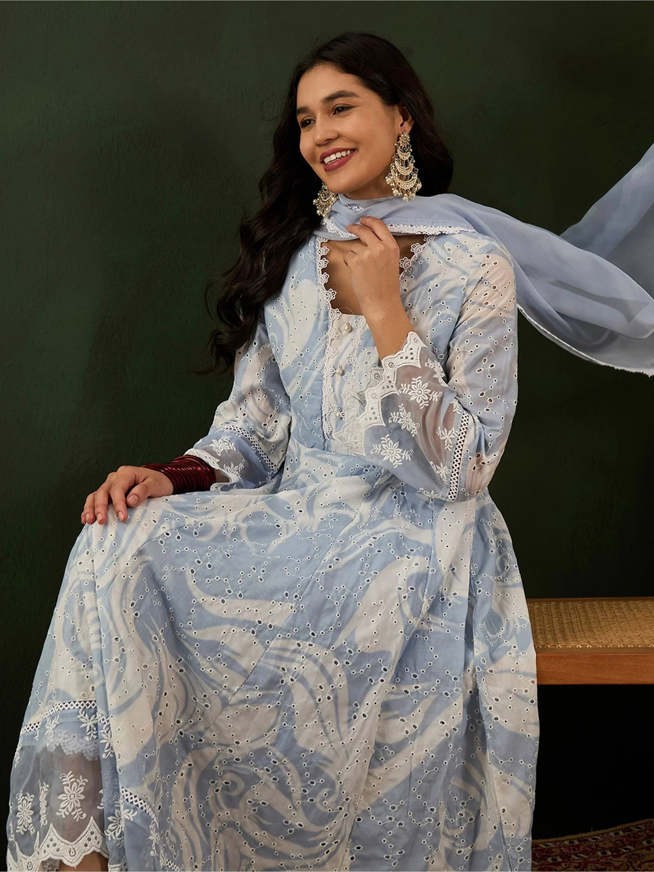 Woman wearing a light blue embroidered ethnic gown with dupatta and statement earrings