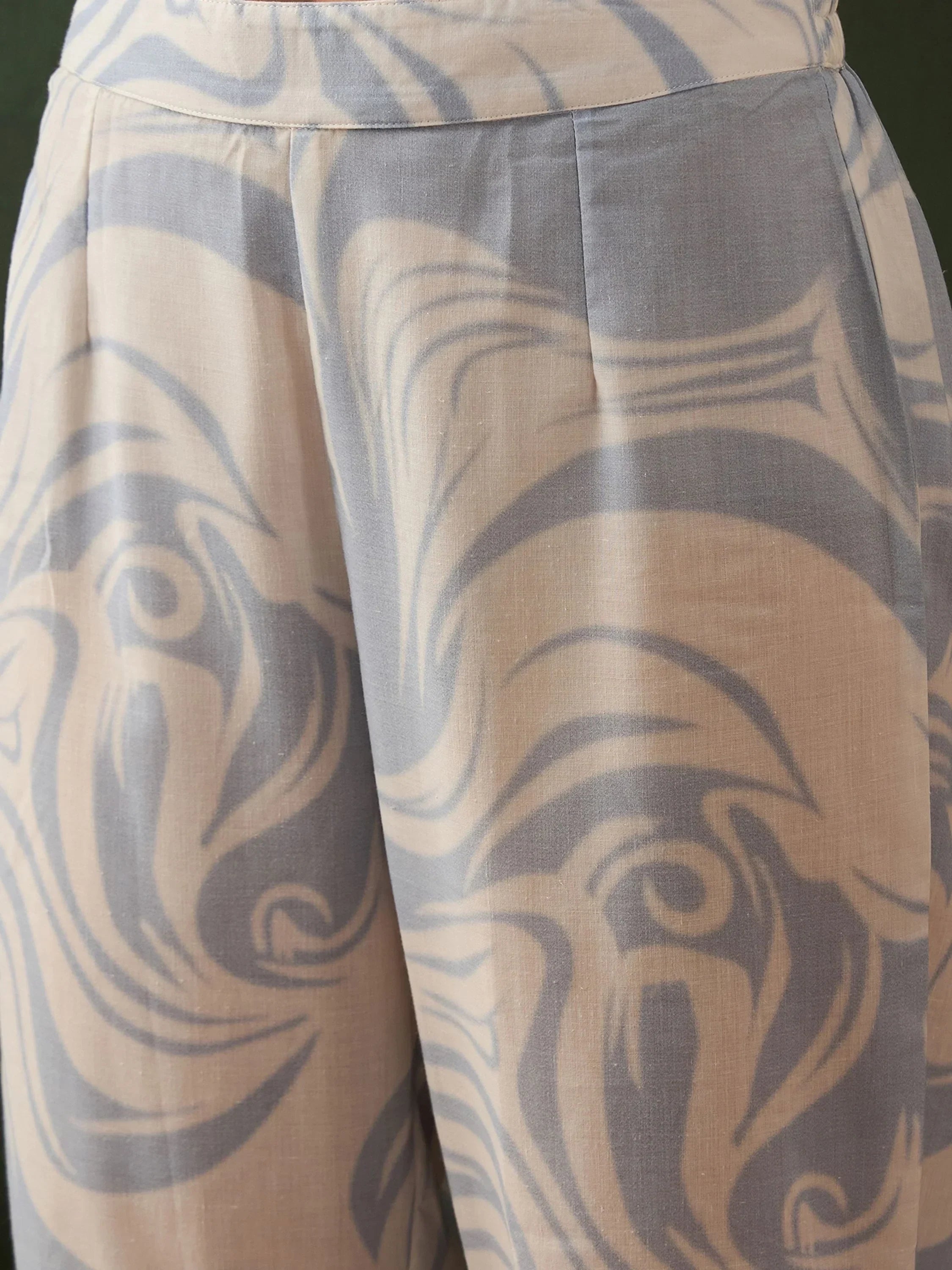 Close-up of light beige and gray ethnic print palazzo pants with abstract swirl patterns
