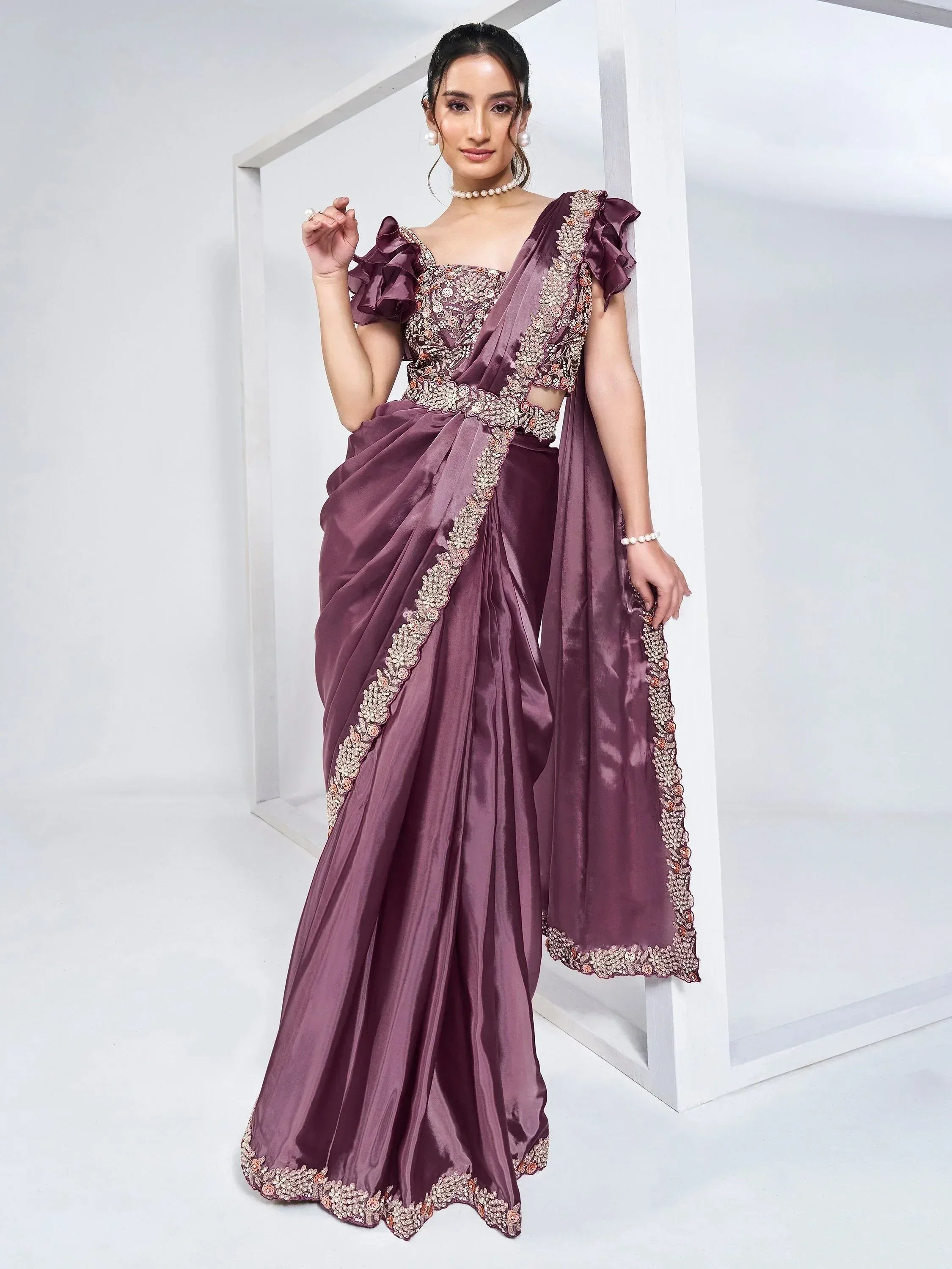 Elegant mauve satin saree with floral embroidery, ruffled sleeves, and pearl accessories for Indian ethnic wear.