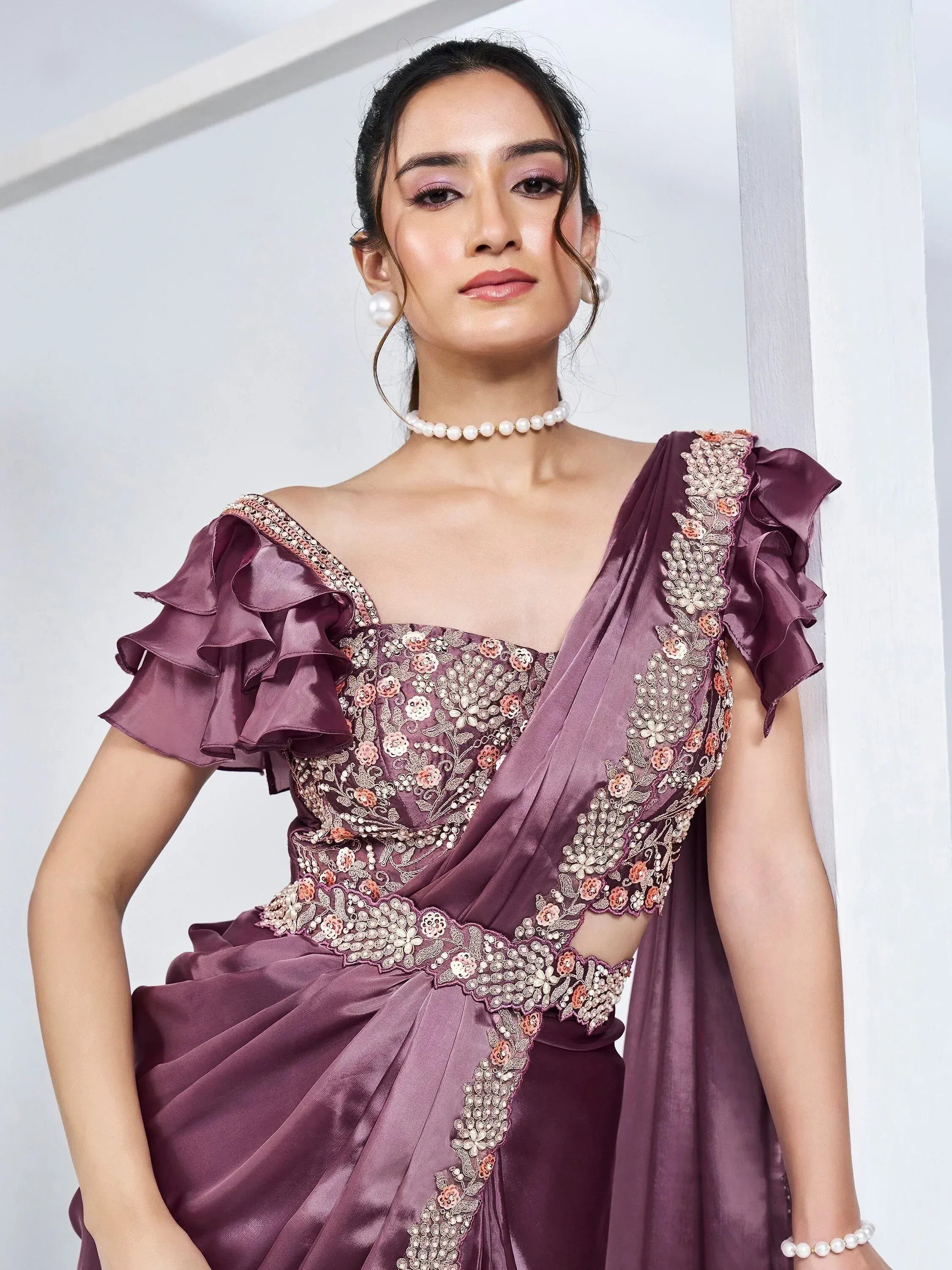 Elegant purple ethnic gown with floral embroidery, ruffled sleeves, and pearl accessories for Indian wear