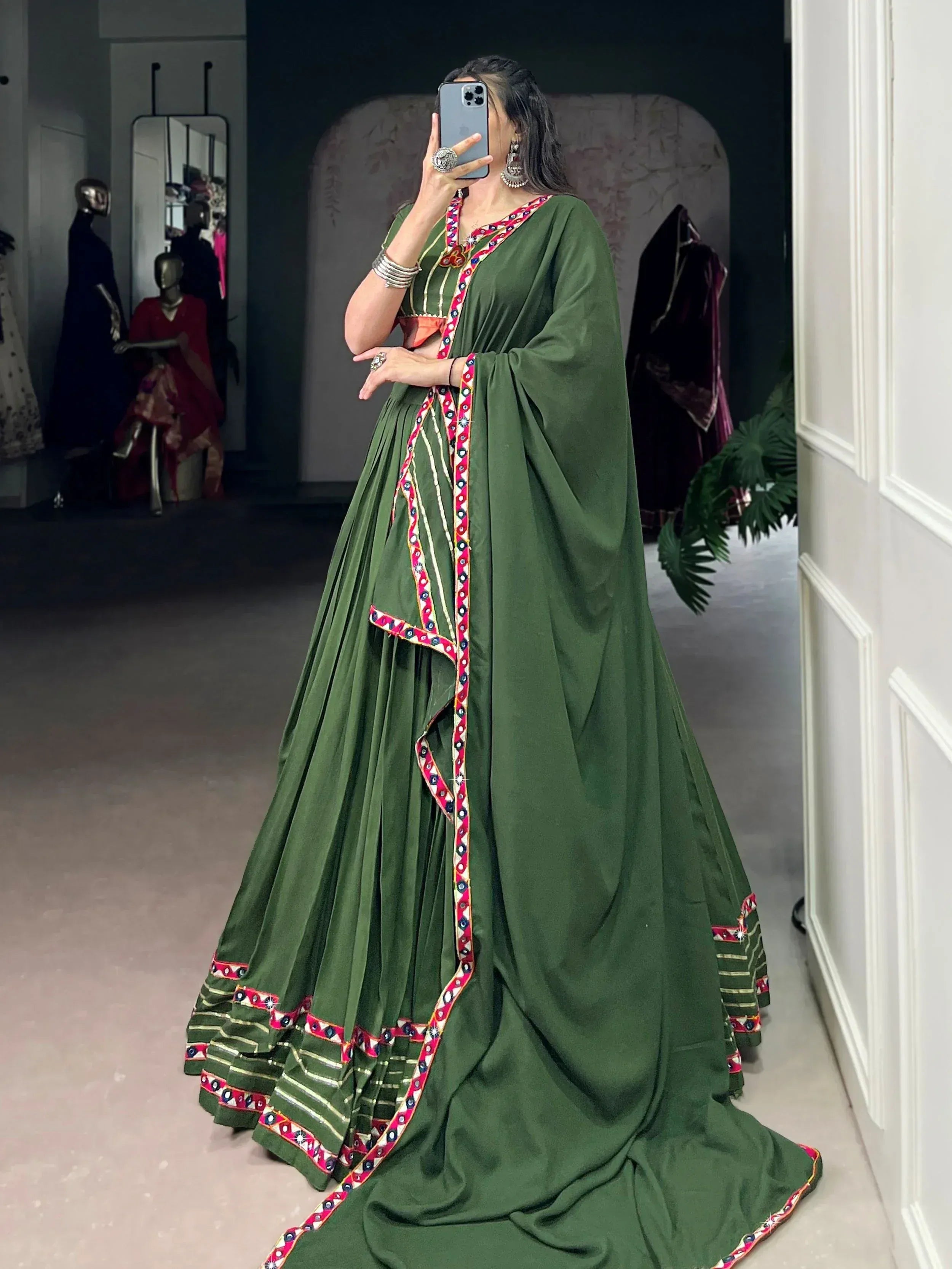 Green ethnic lehenga choli with mirror work and colorful embroidery, perfect for Indian weddings and festive occasions.