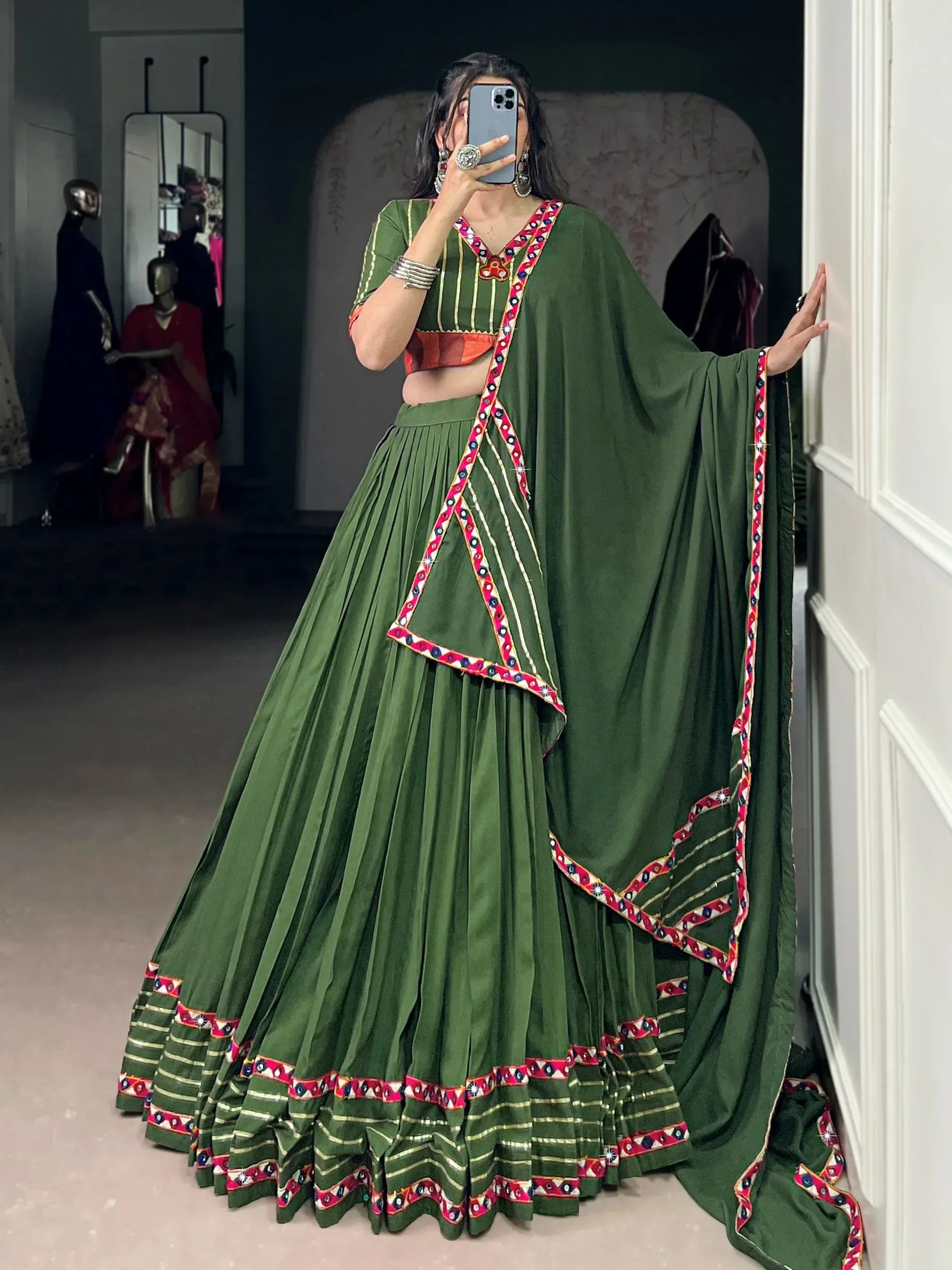 Green ethnic lehenga choli with mirror work and colorful embroidery, perfect for Indian weddings or festive occasions.