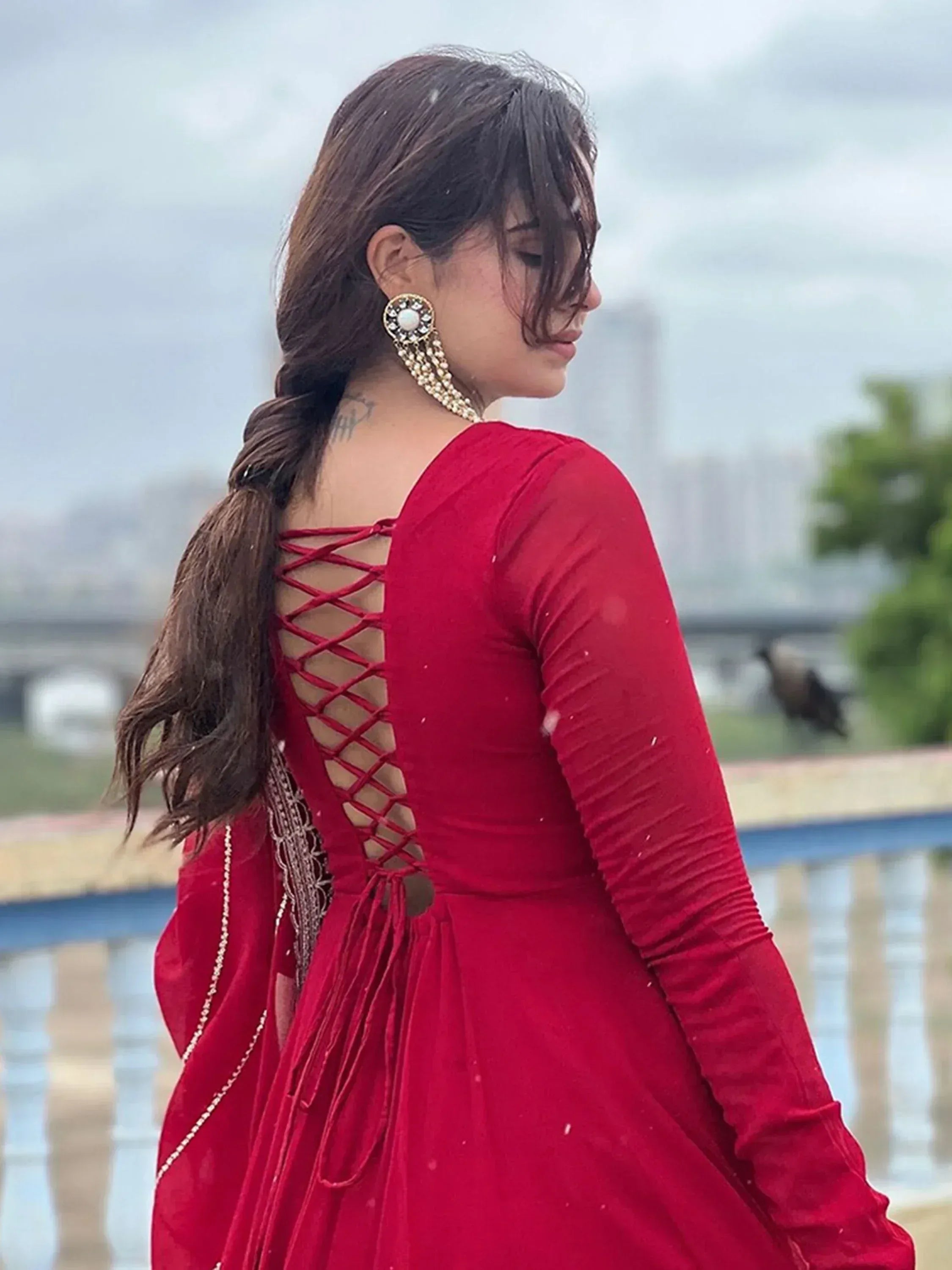 Red ethnic gown with lace-up back, long sleeves, and pearl earrings for Indian wear