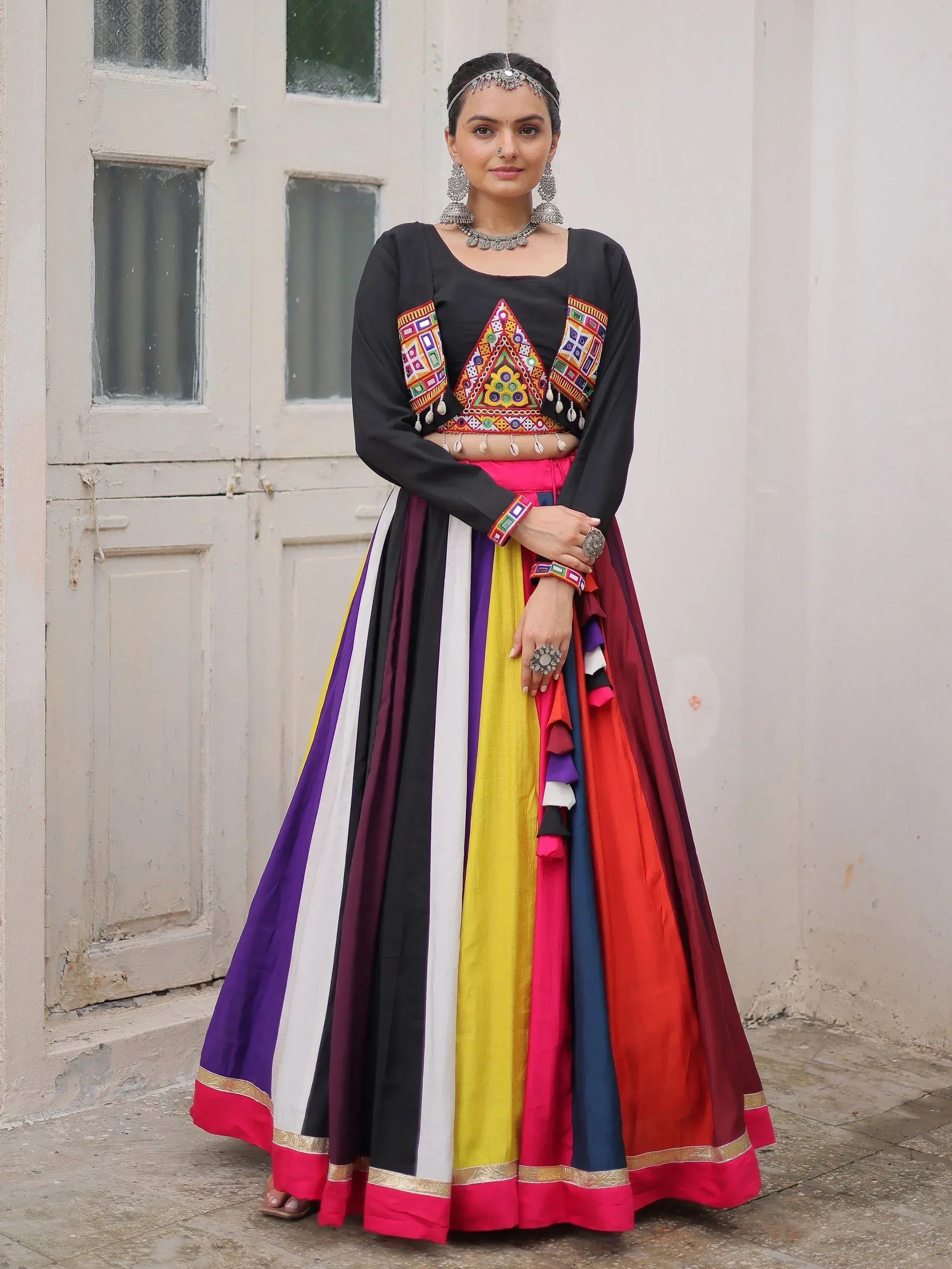 Woman in colorful Indian ethnic wear with embroidered black top and multi-stripe skirt, traditional jewelry