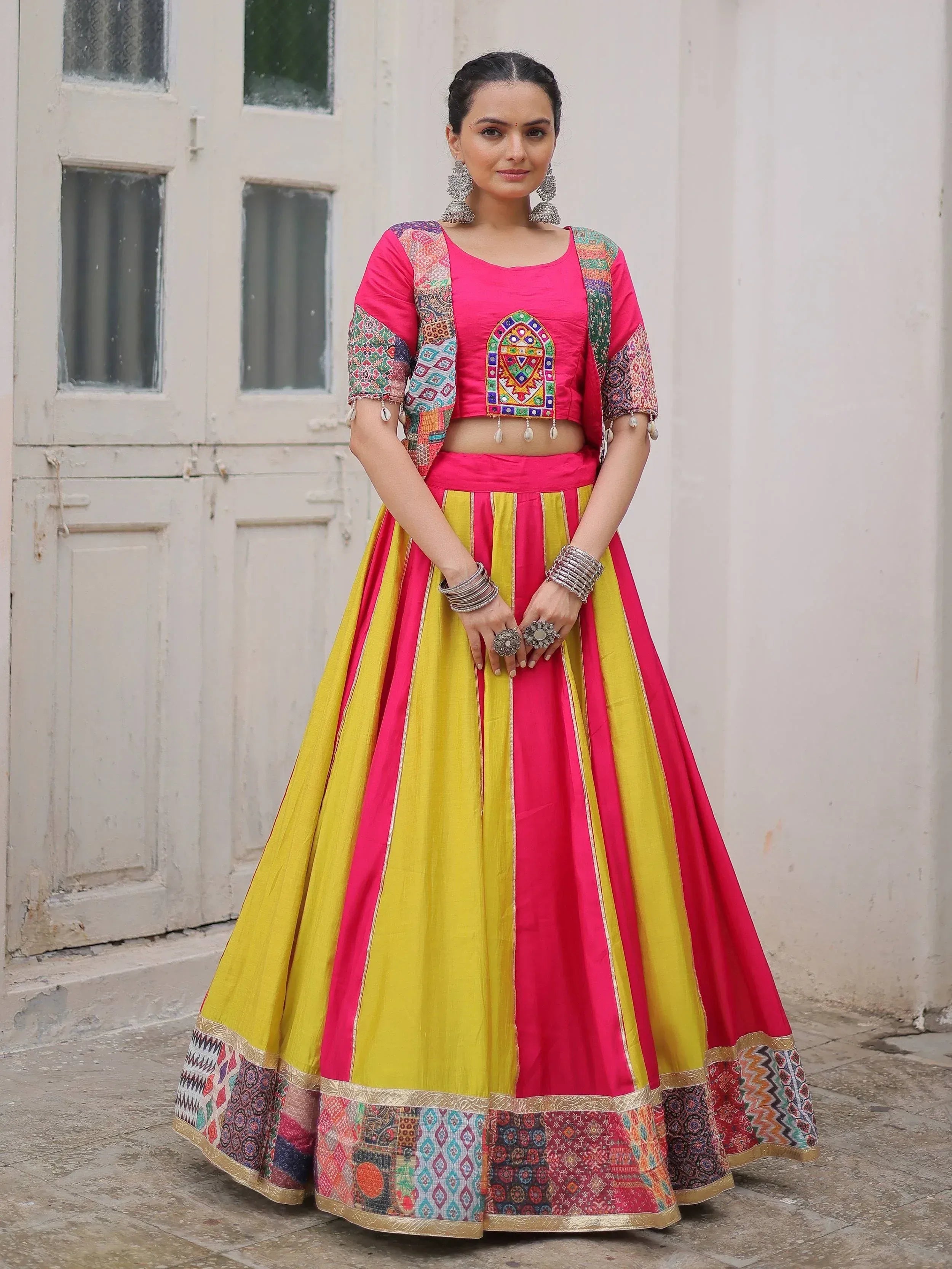 Vibrant pink and yellow lehenga choli with embroidered crop top and patchwork dupatta, perfect for Indian ethnic occasions.