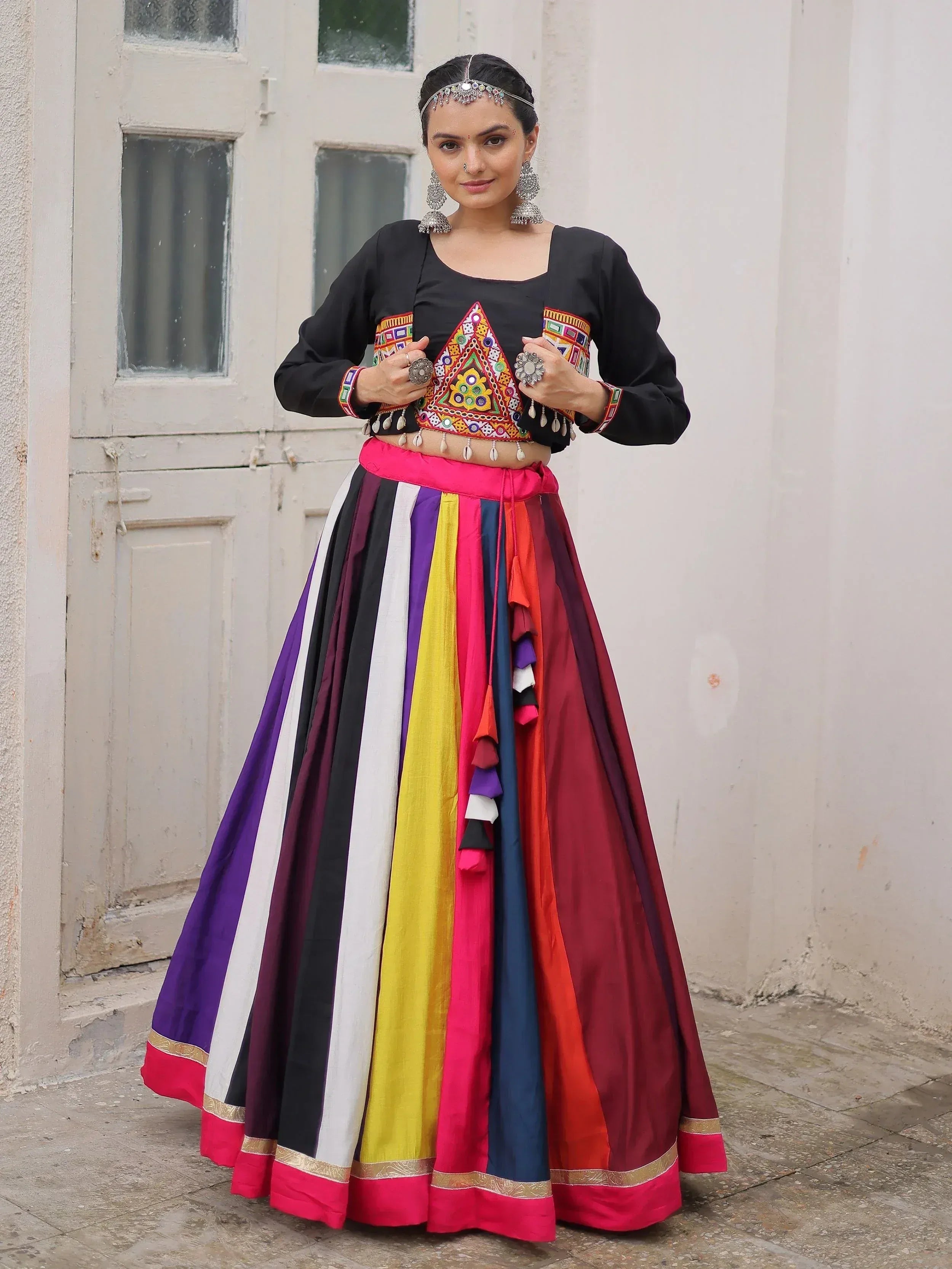Woman in colorful Indian ethnic wear with embroidered black top and striped skirt, traditional jewelry