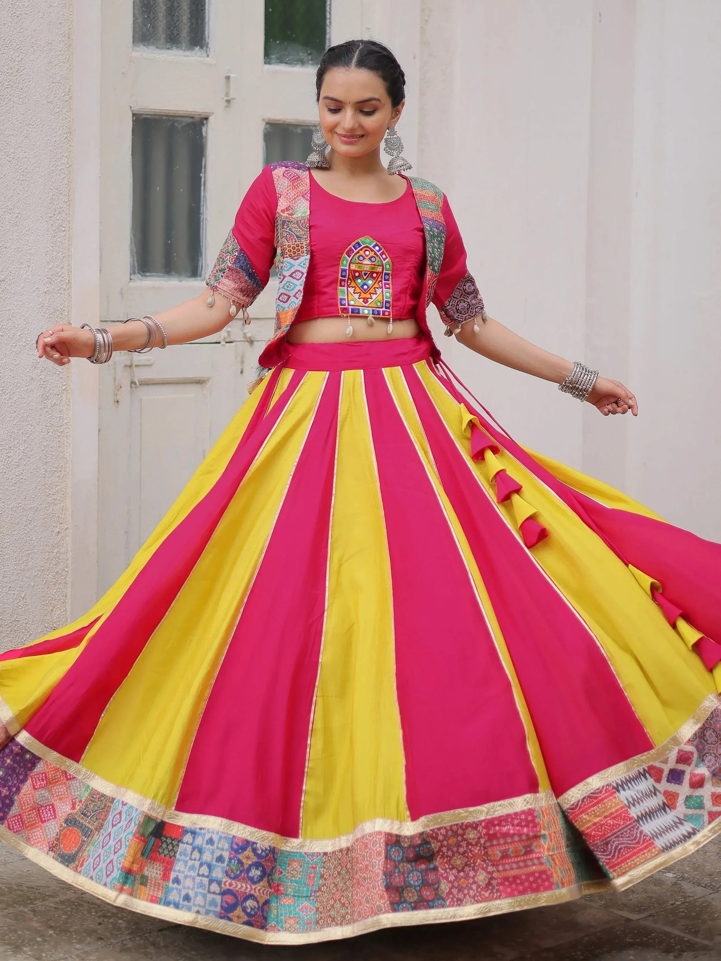 Vibrant pink and yellow Indian lehenga choli with embroidered blouse and patchwork skirt, perfect for festive occasions.