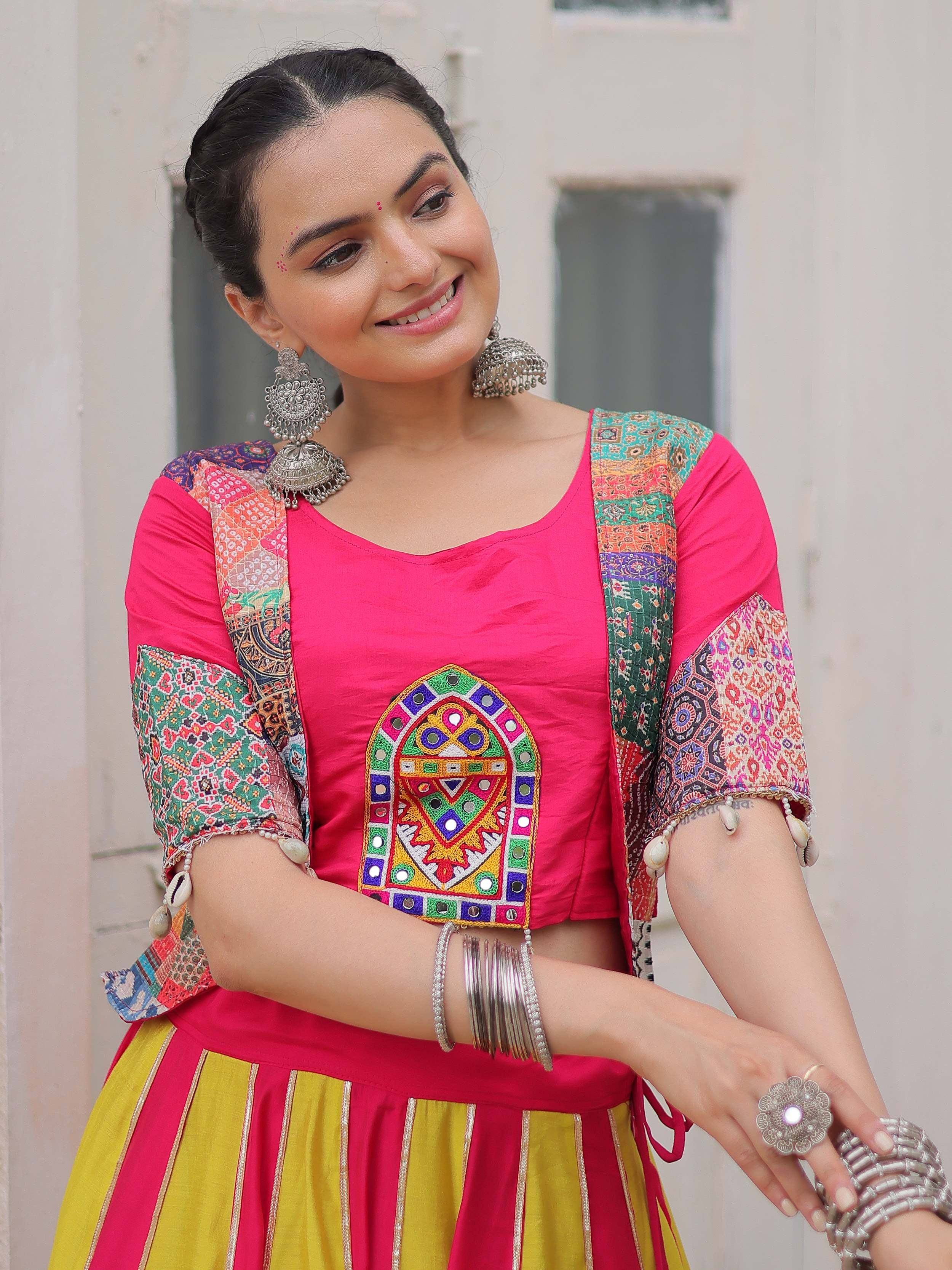 Vibrant pink and yellow ethnic lehenga choli with mirror work, patchwork sleeves, and traditional silver jewelry