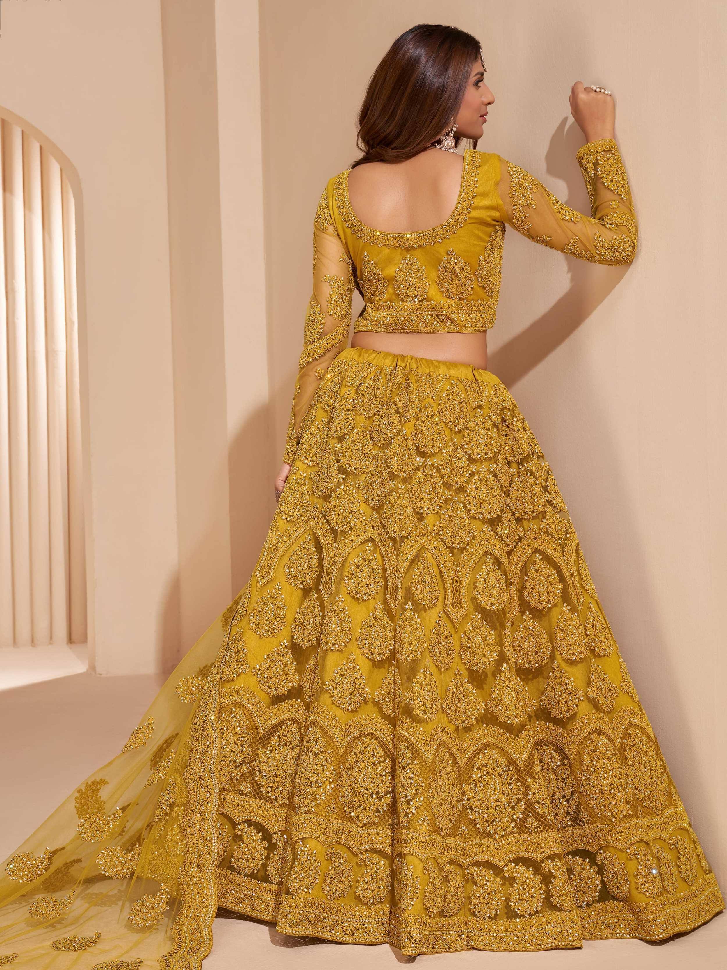 Yellow designer lehenga choli with heavy embroidery and sheer sleeves, perfect for Indian weddings and festive occasions.