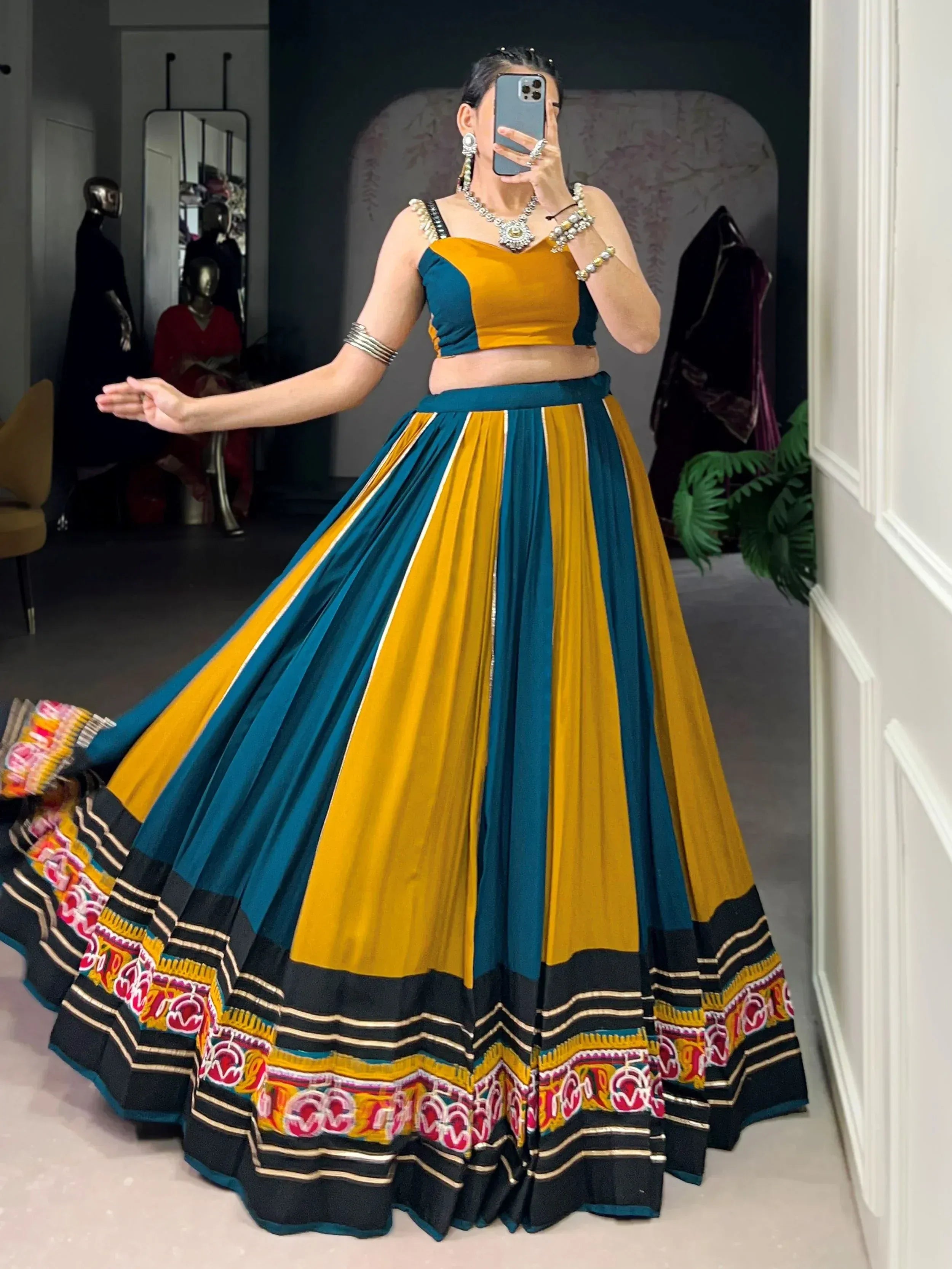 Woman in vibrant yellow and teal lehenga choli with embroidered border, perfect for Indian ethnic wear occasions