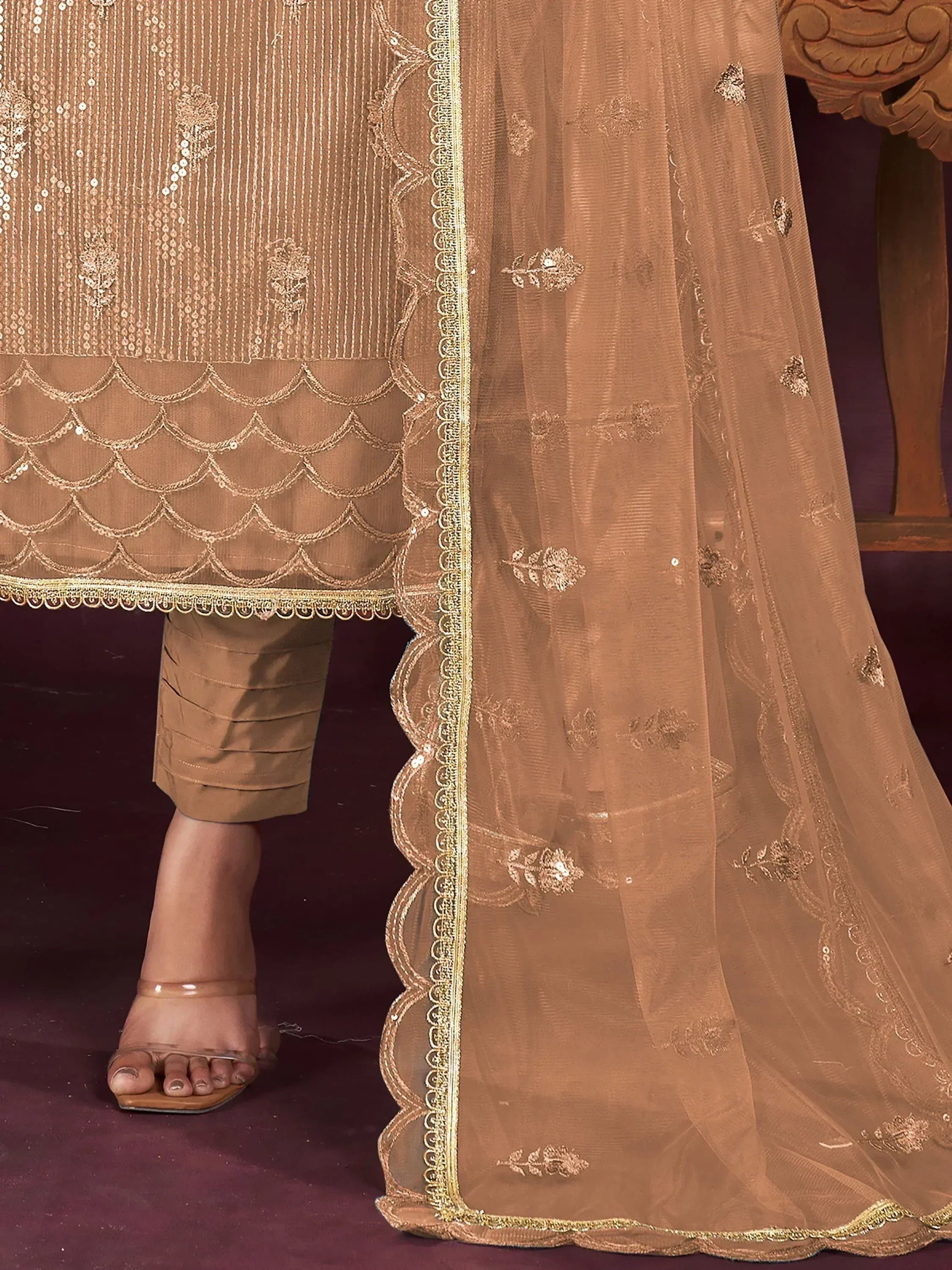 Elegant brown ethnic suit with gold embroidery, scalloped hem, and sheer dupatta for festive occasions