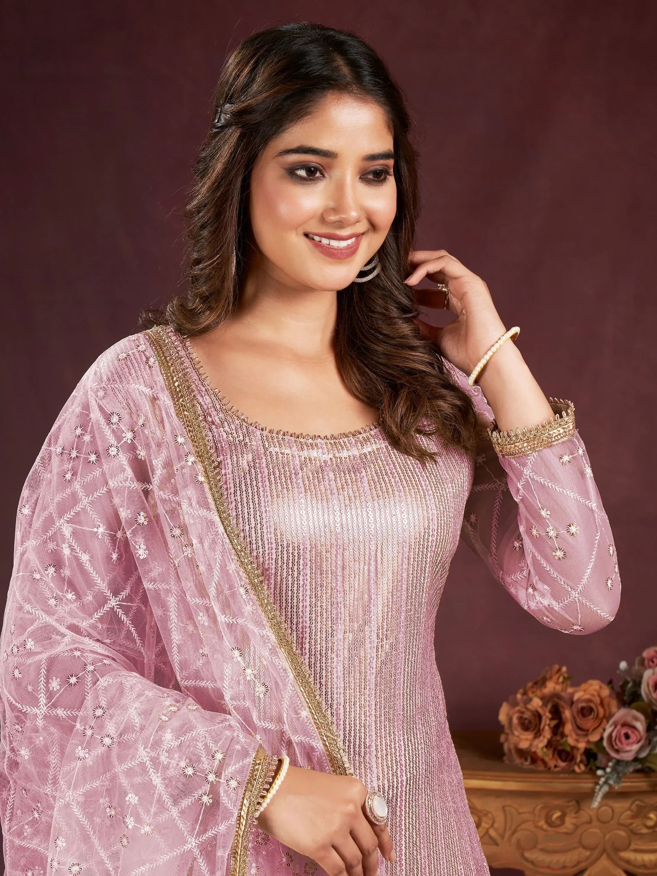 Woman in pink embroidered ethnic gown with net dupatta and gold jewelry