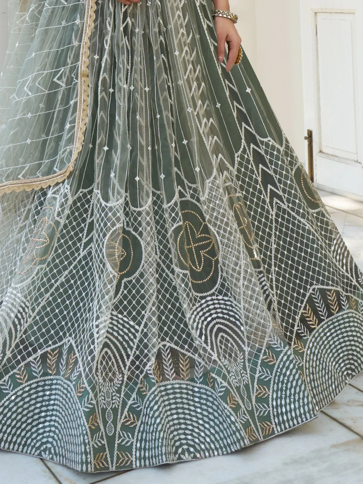 Olive green designer lehenga with intricate white and gold embroidery, perfect for Indian ethnic wear events.