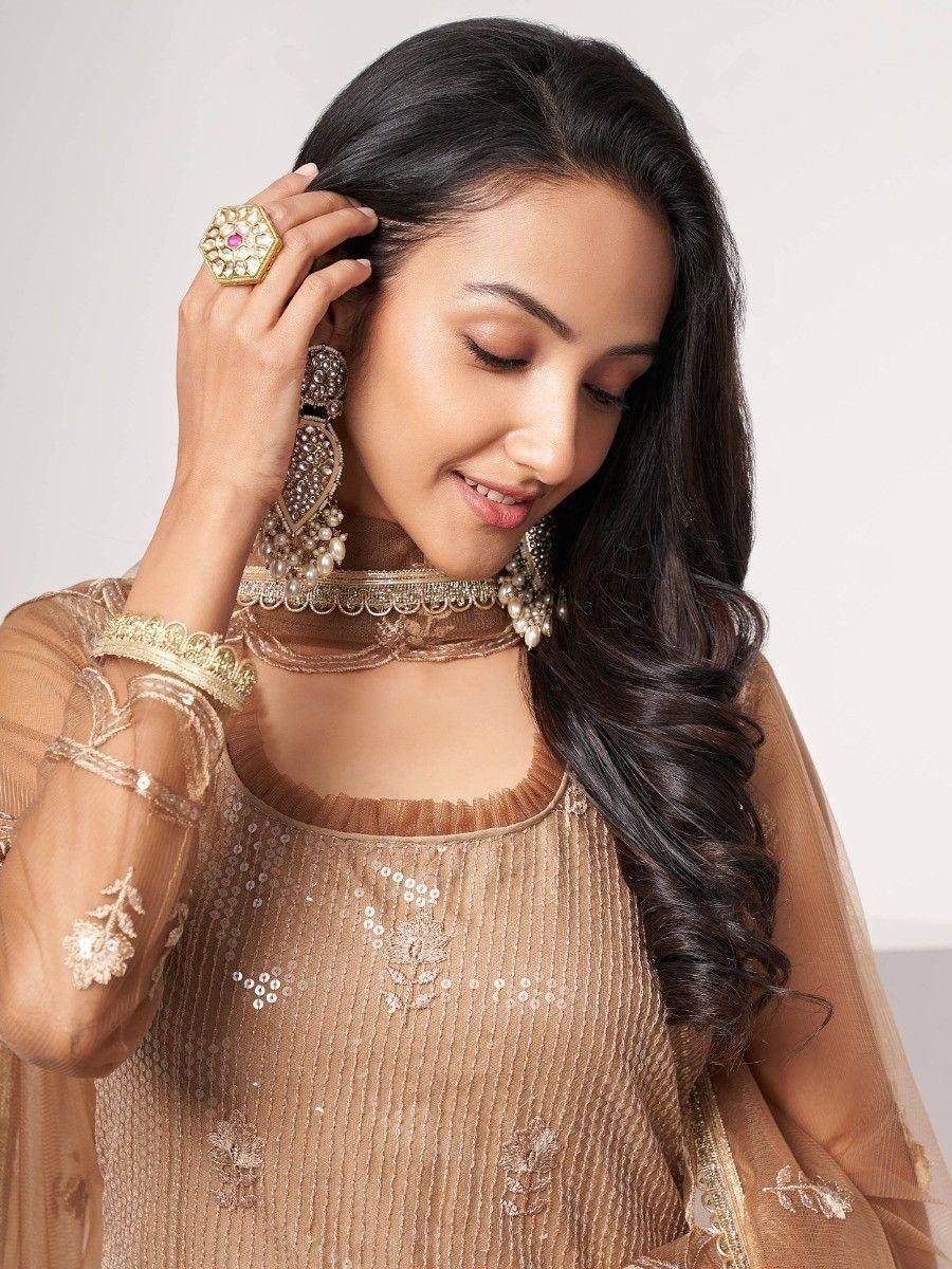Elegant woman in gold embroidered ethnic gown with pearl choker and statement earrings