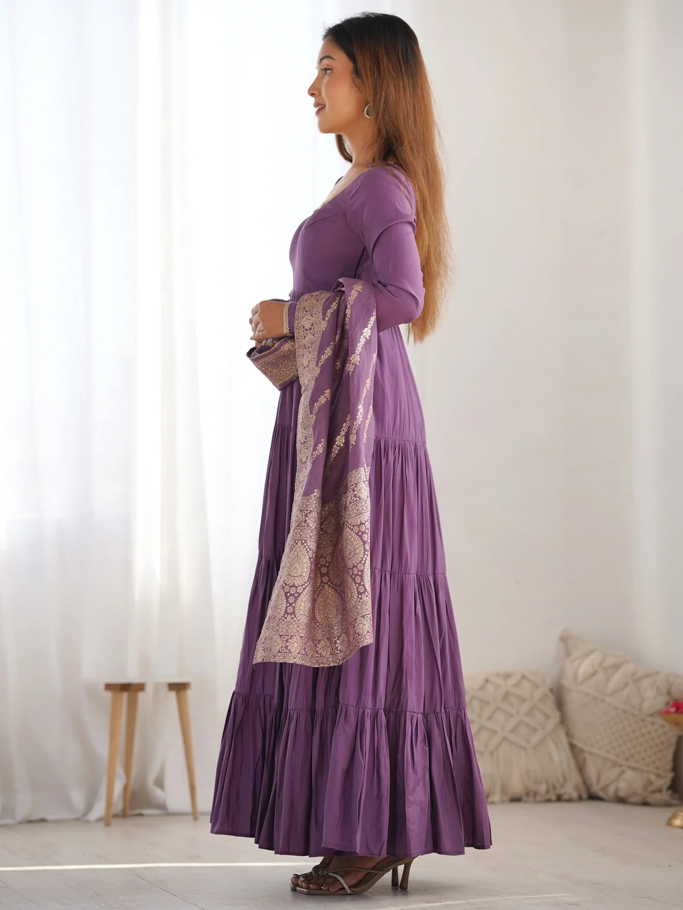 Woman in a purple ethnic gown with gold embroidered dupatta, side profile view