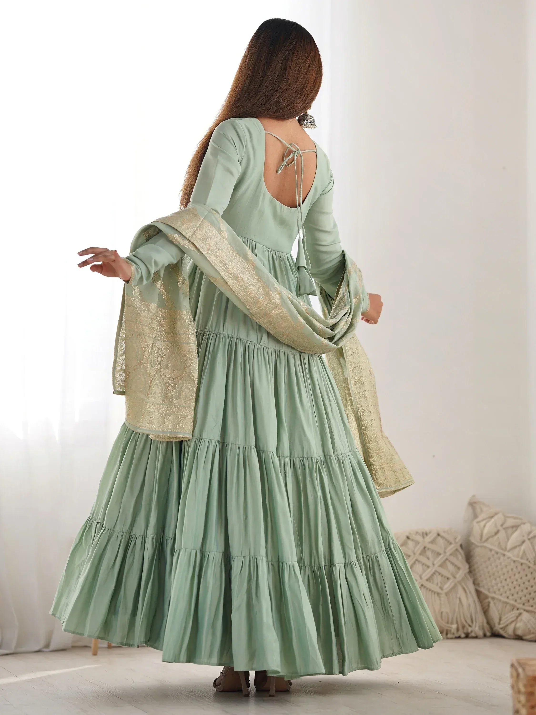 Woman in sage green Anarkali gown with gold embroidered dupatta, back tie detail