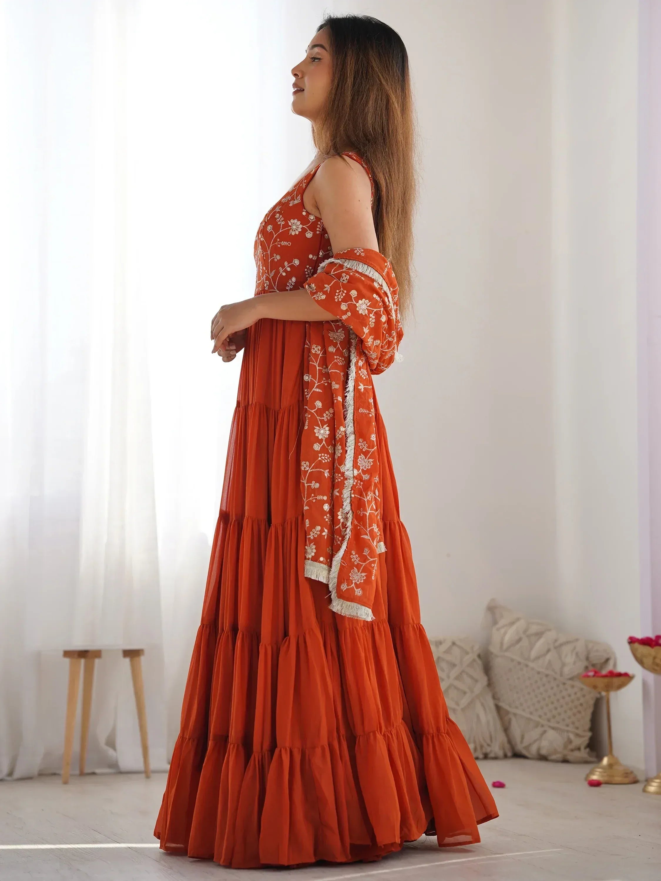 Orange embroidered ethnic gown with tiered skirt and floral detailing, perfect for Indian occasions