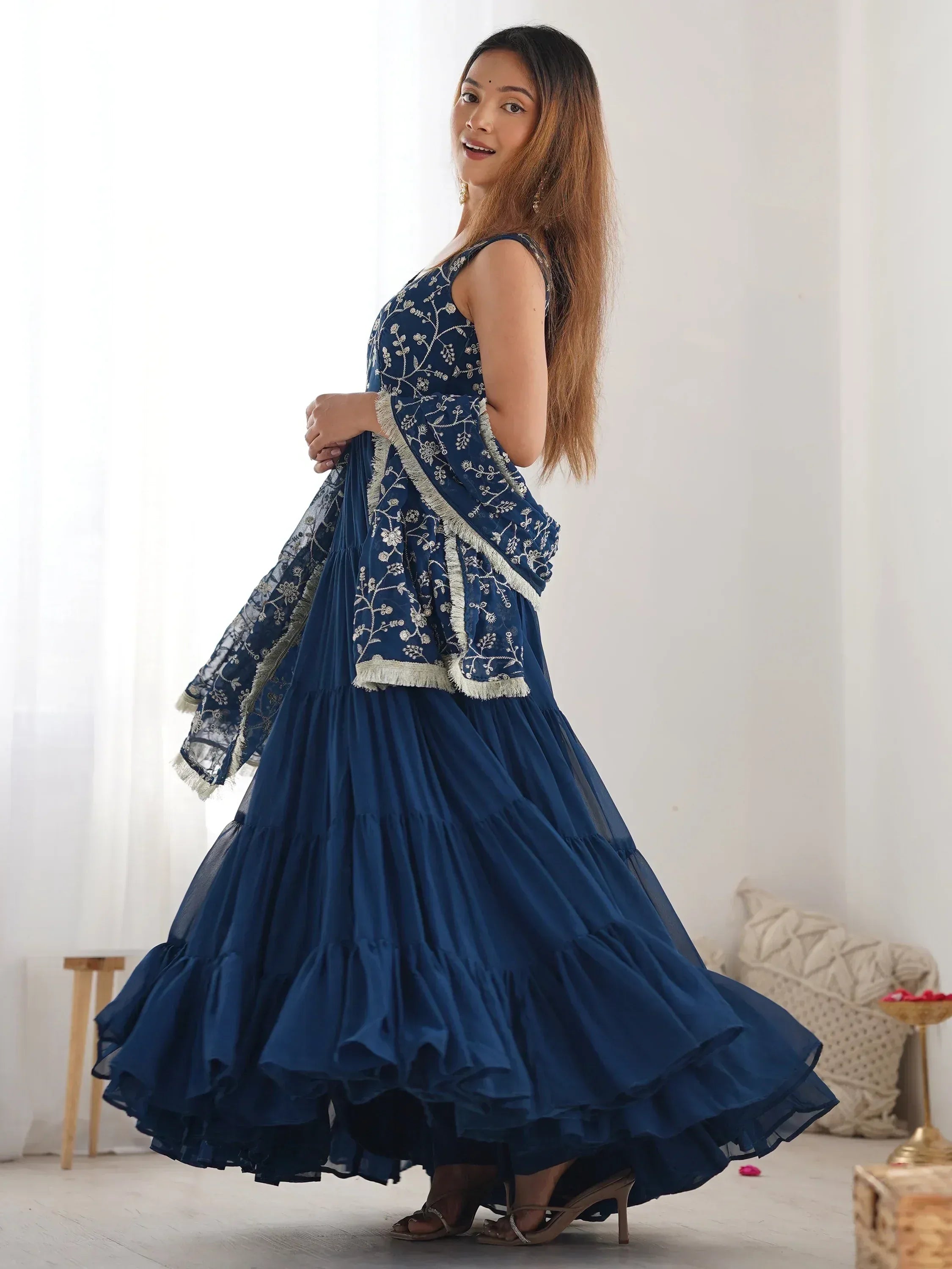 Woman wearing navy blue embroidered lehenga choli with dupatta in bright indoor setting