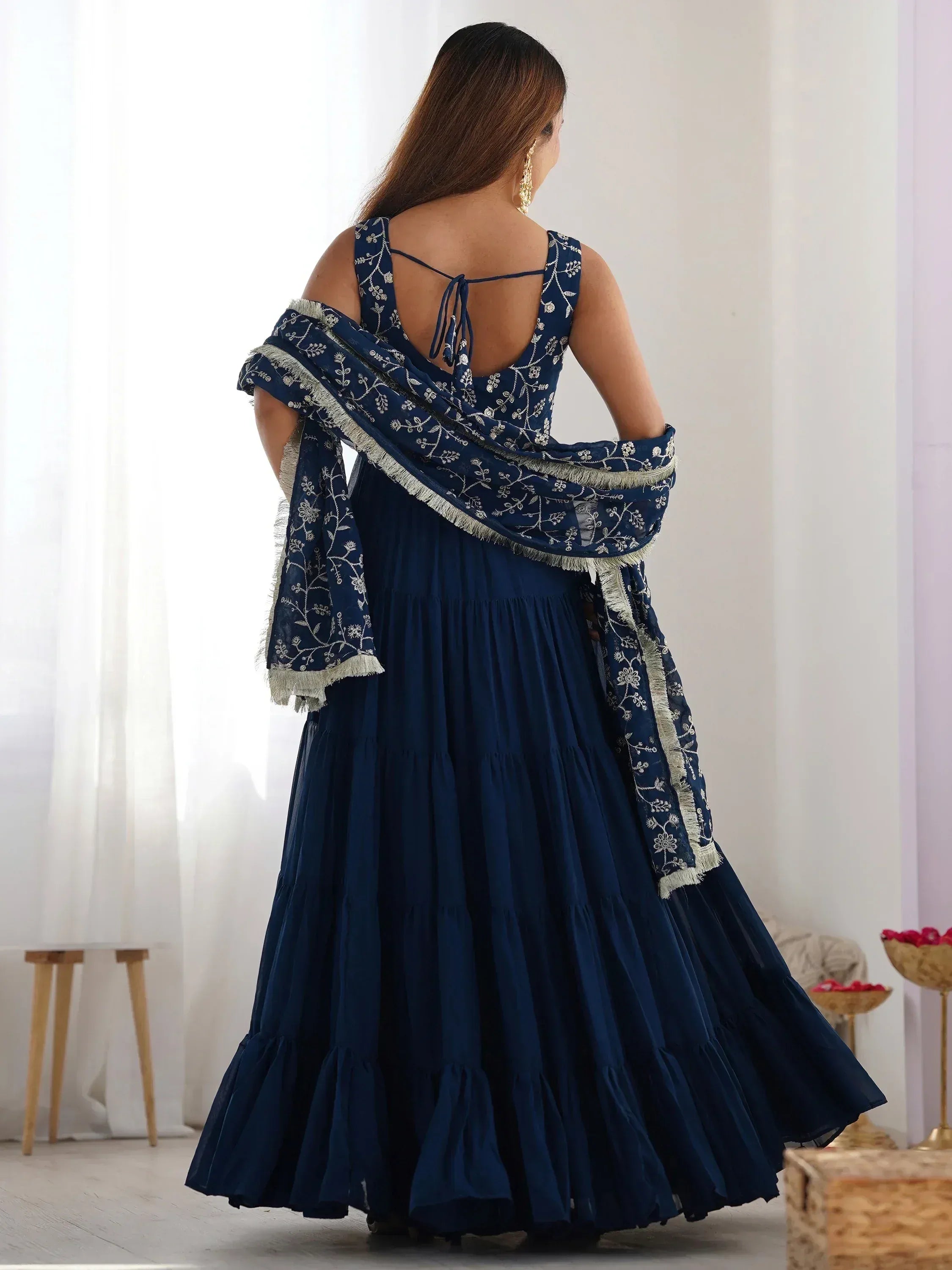 Woman wearing navy blue embroidered ethnic gown with matching dupatta, back view