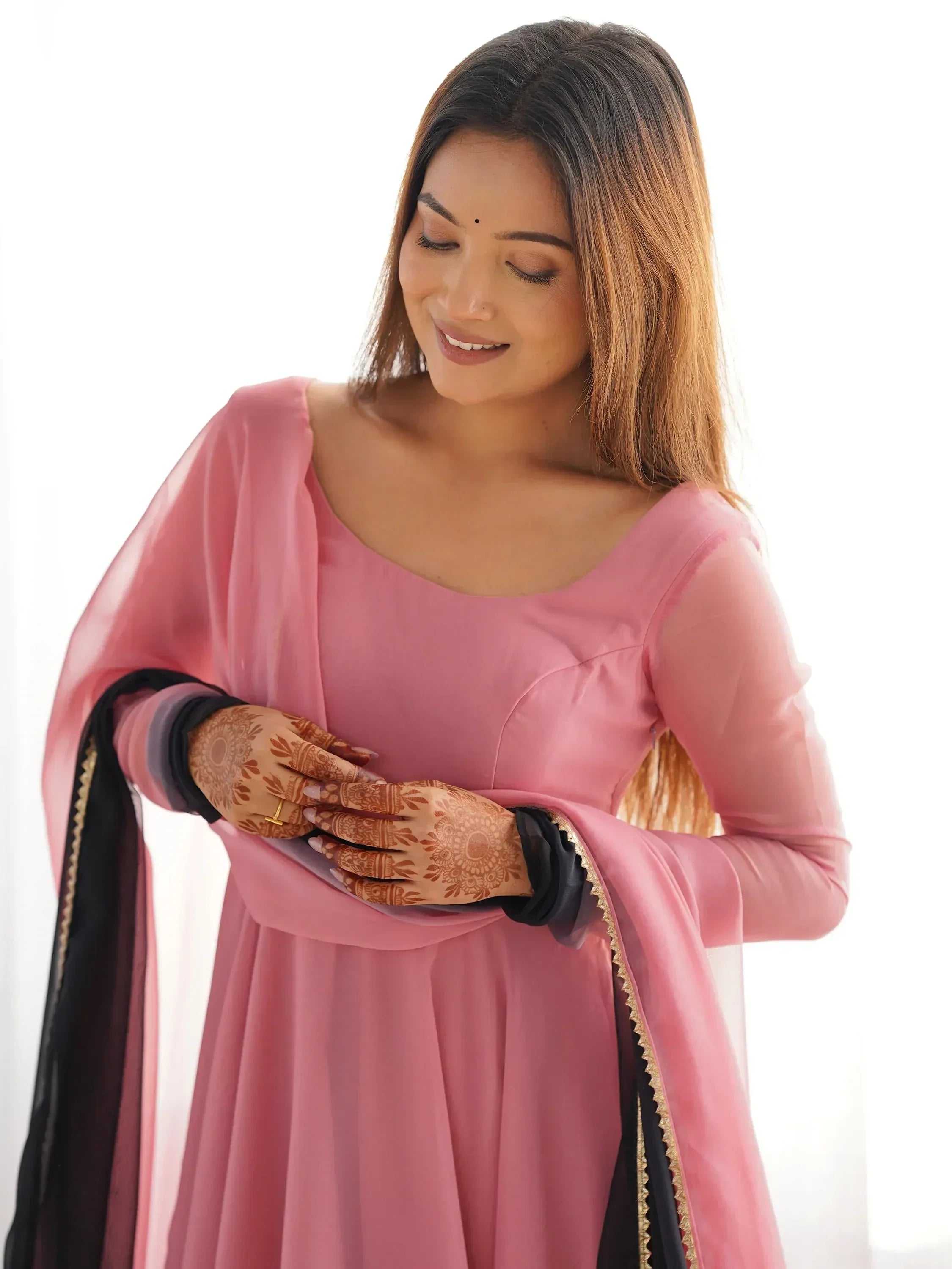 Woman in pink ethnic gown with black dupatta, henna hands, perfect for Indian occasions