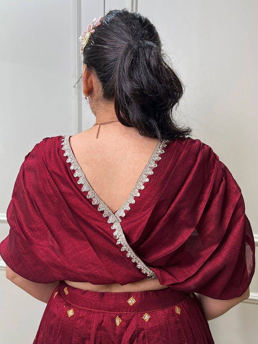 Maroon ethnic lehenga choli with embroidered back neckline and floral hair accessory
