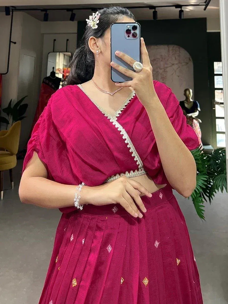 Woman in magenta ethnic lehenga choli with gold embroidery, taking mirror selfie in boutique